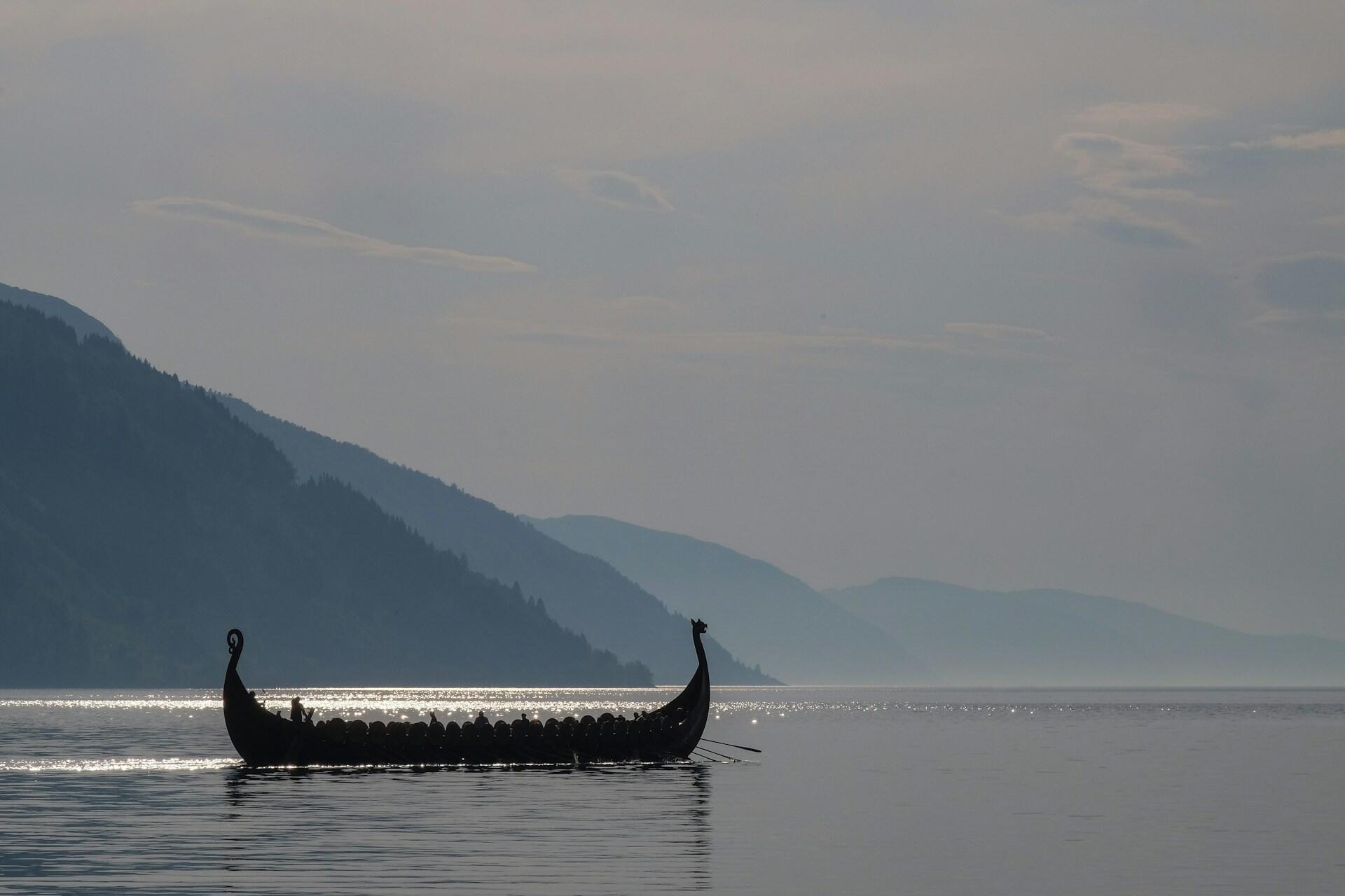 A viking boat on quiet waters on a cloudy day.