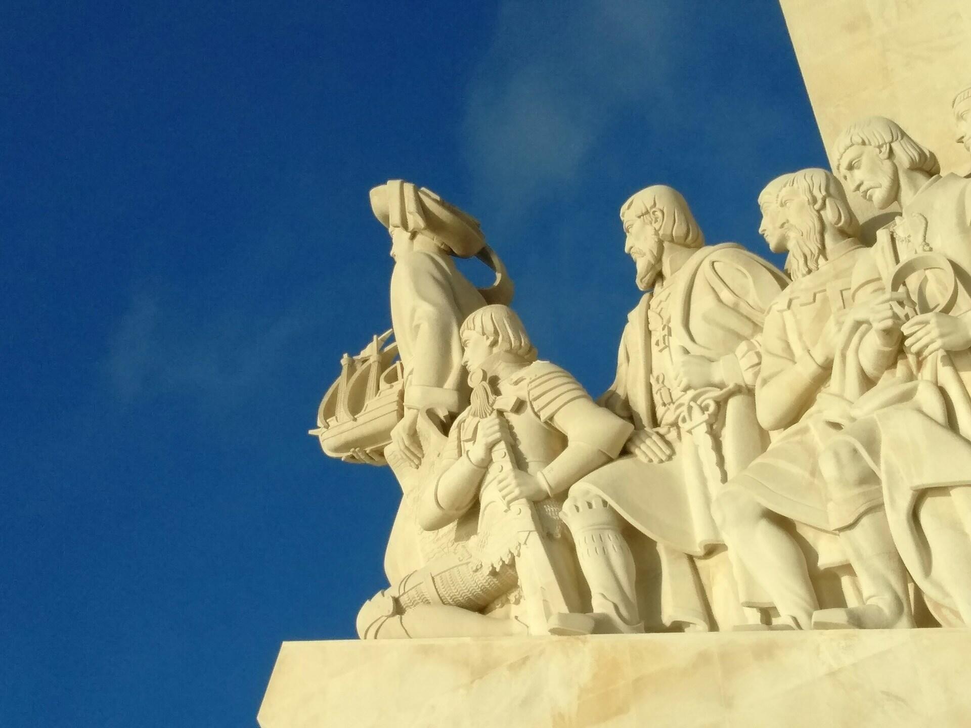statue of explorers looking into a blue sky