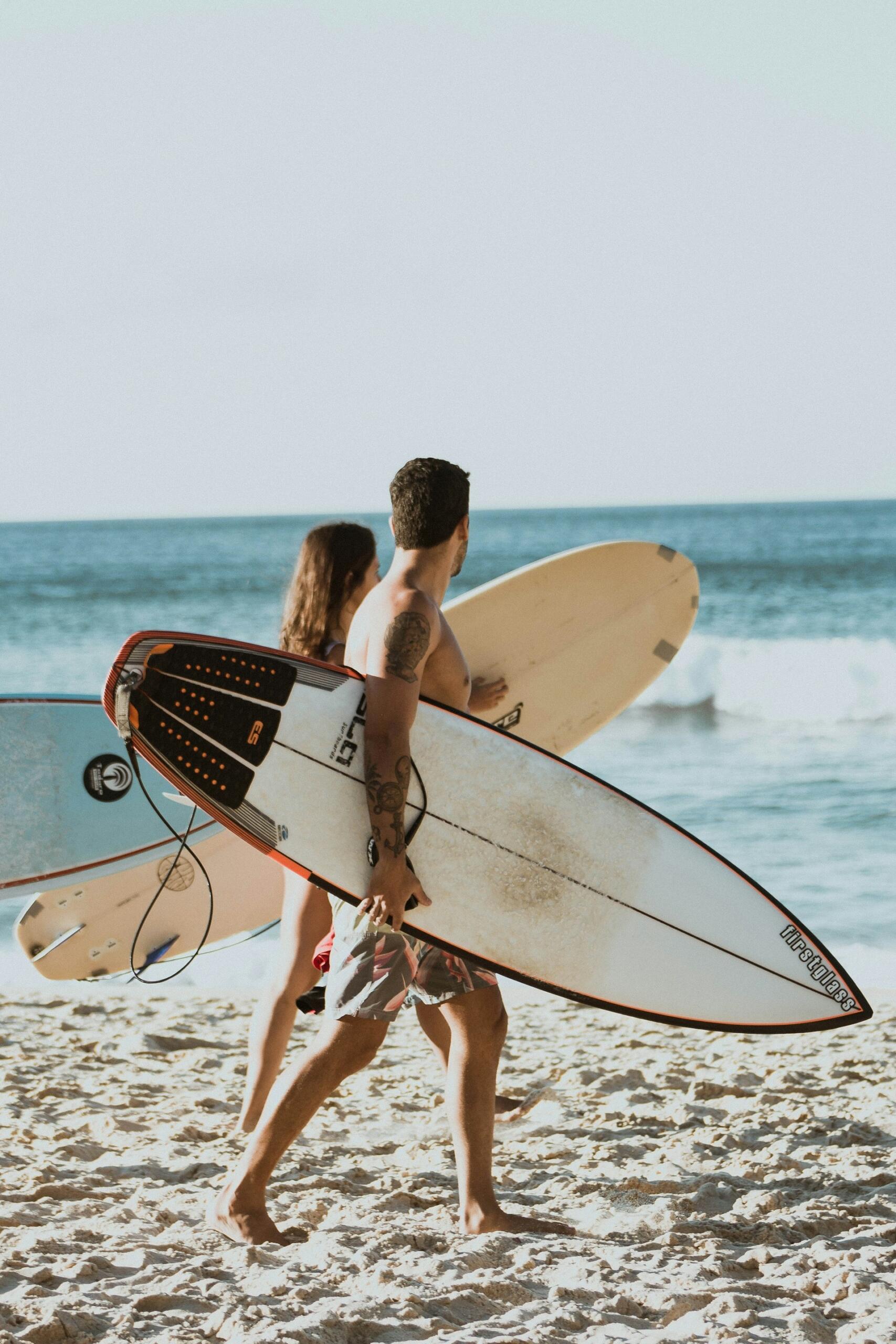 Two people with surfboards walking on the beach.