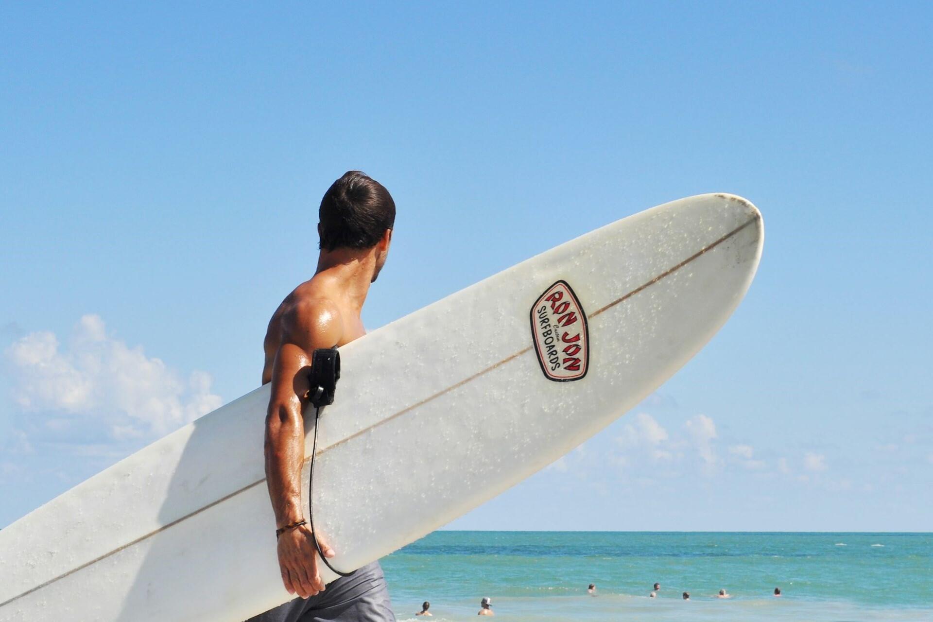 A surfer carrying their board.