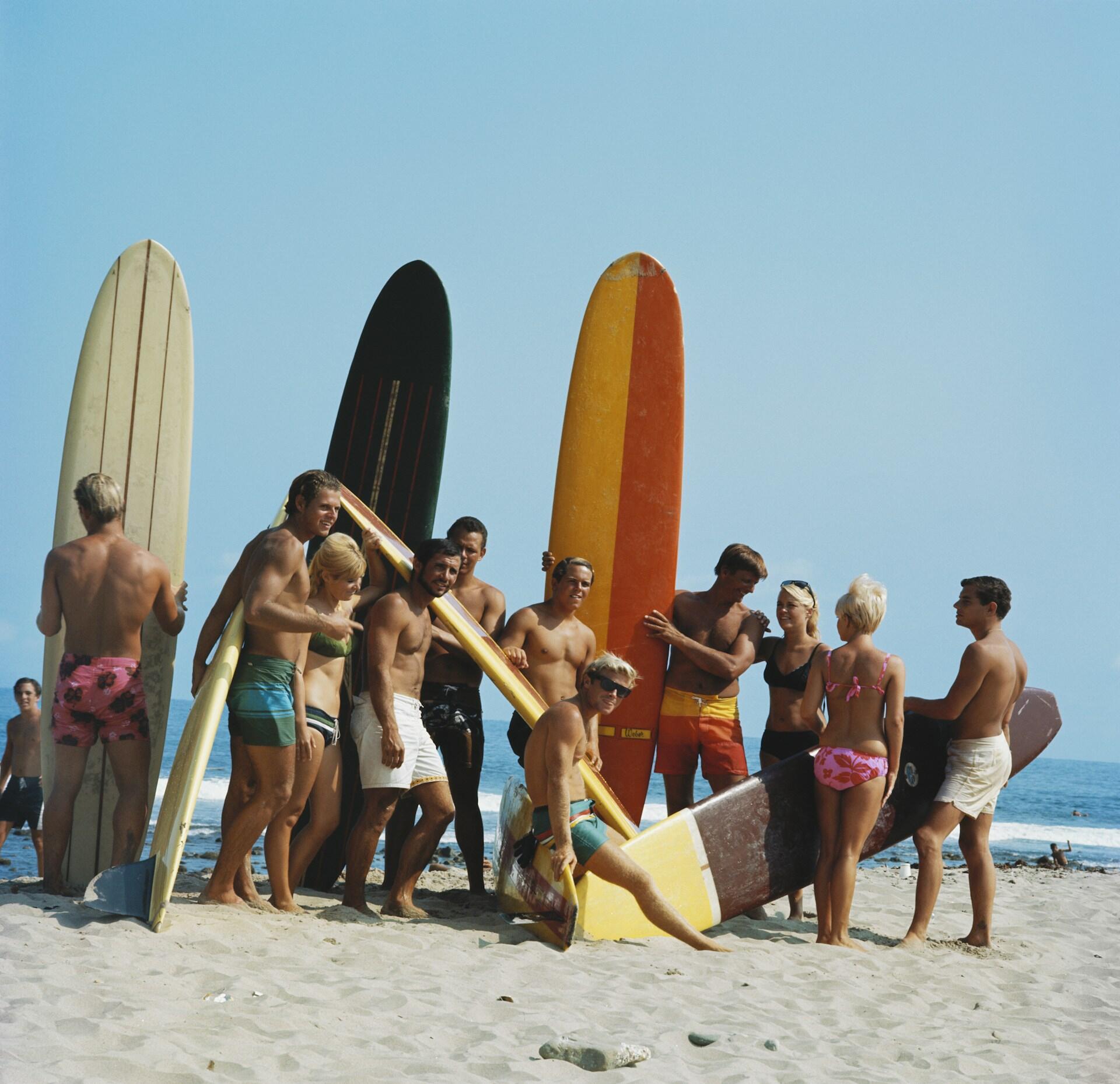 A group of people in beach wear with surfboards.