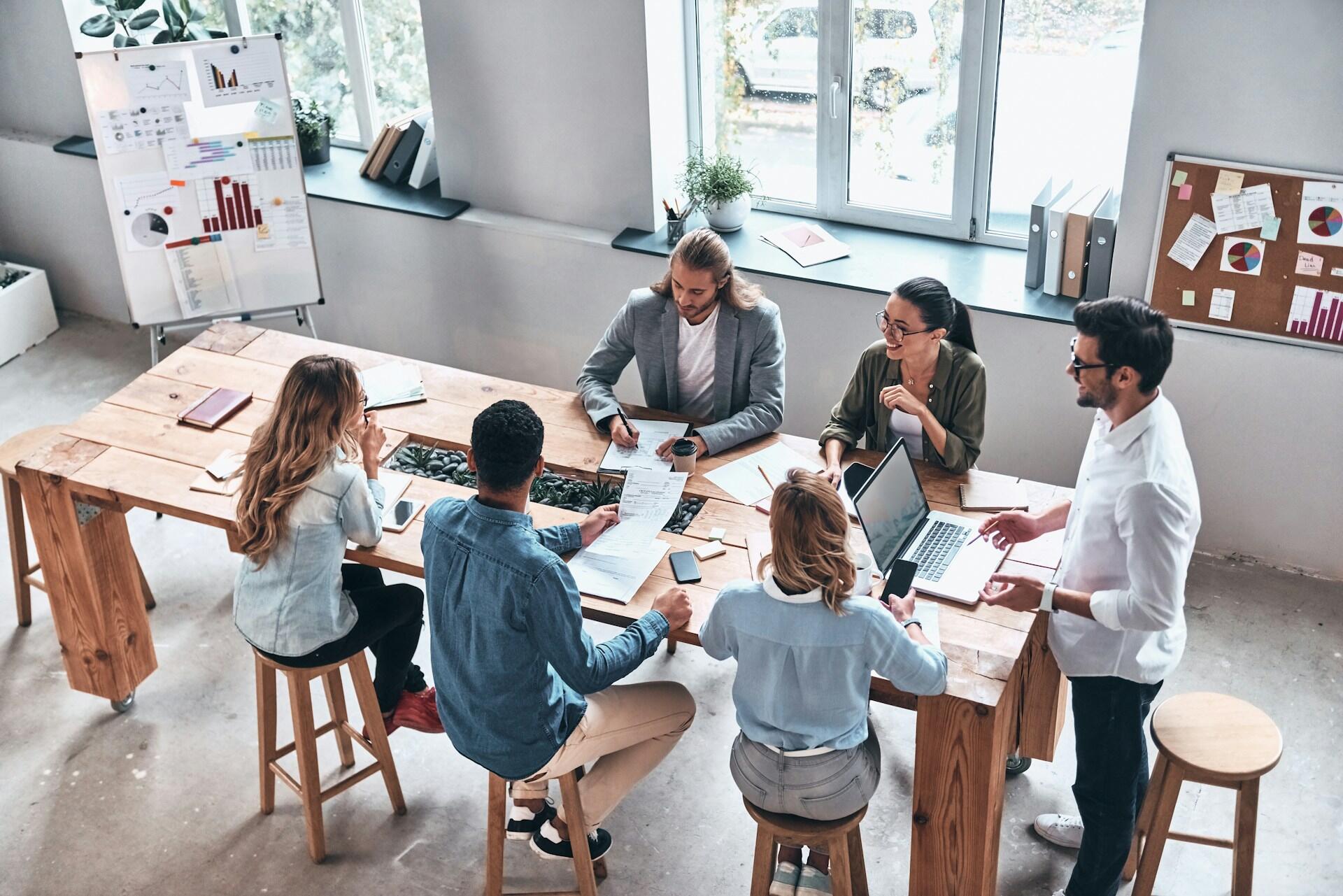 A group of people sitting around a long wooden table.