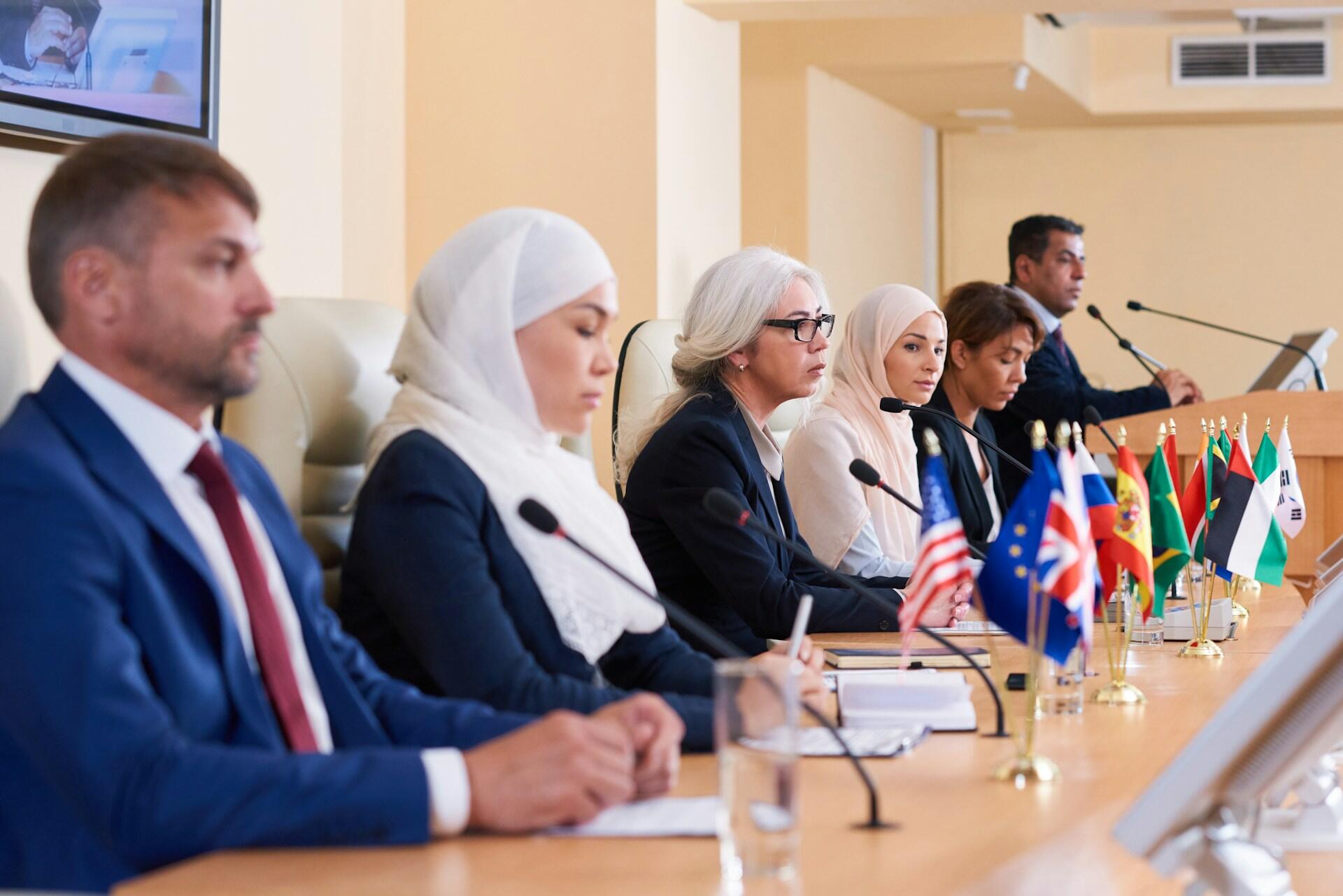 A group of people wearing business attire sitting at a long table.