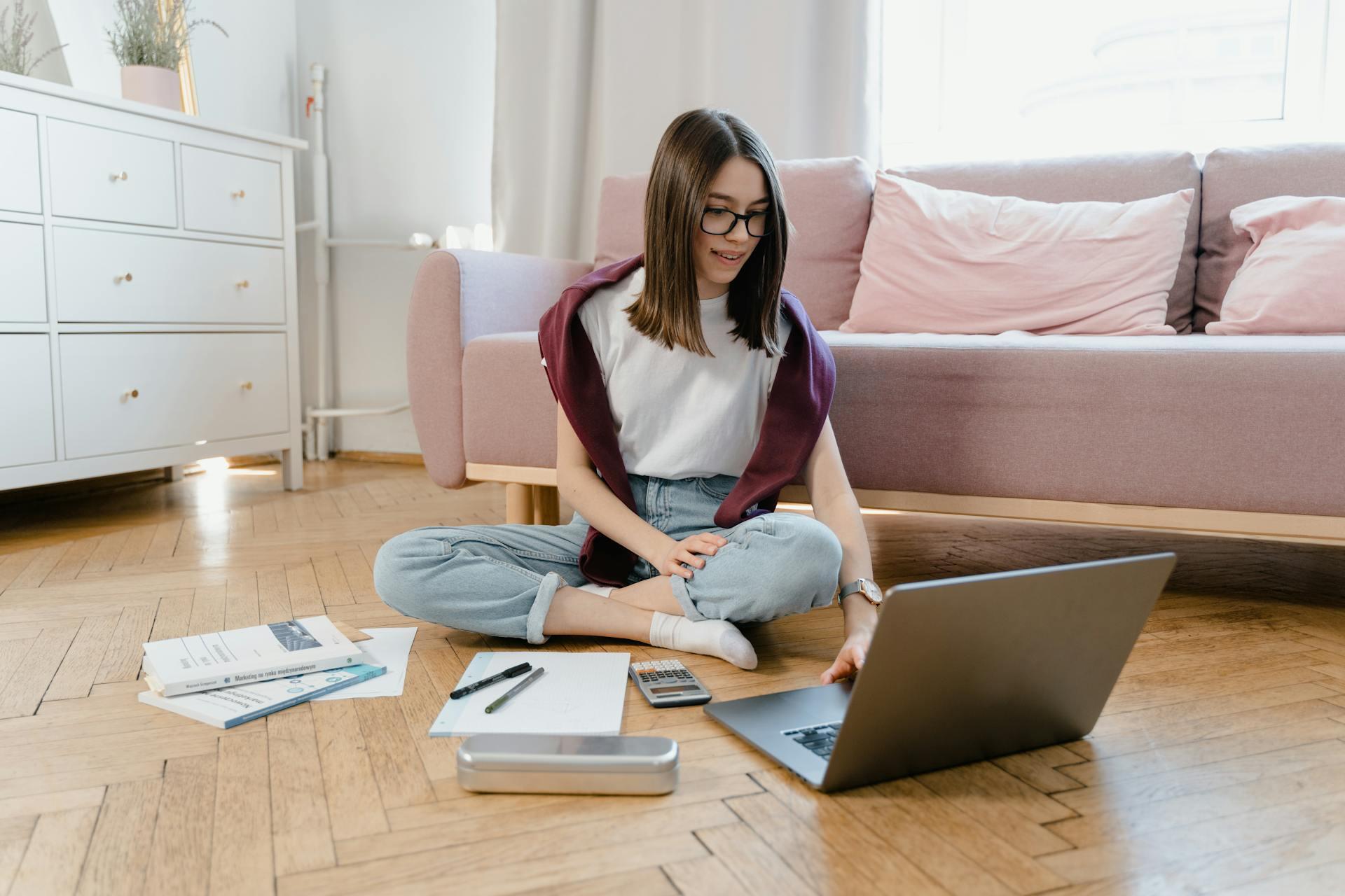 student doing homework at home while sitting on the floor, smiling