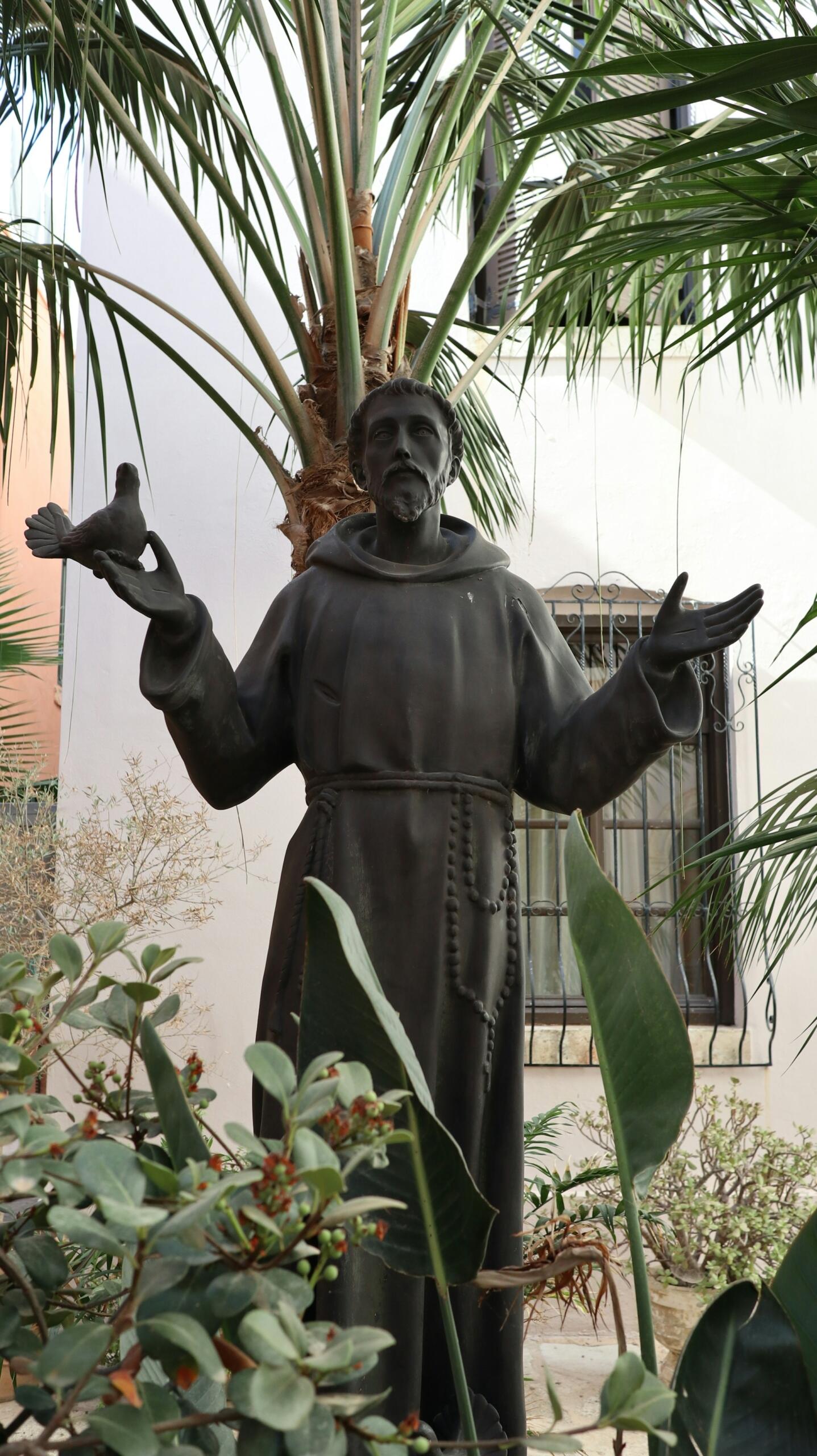 A statue of a man in robes with his hands held at shoulder height.