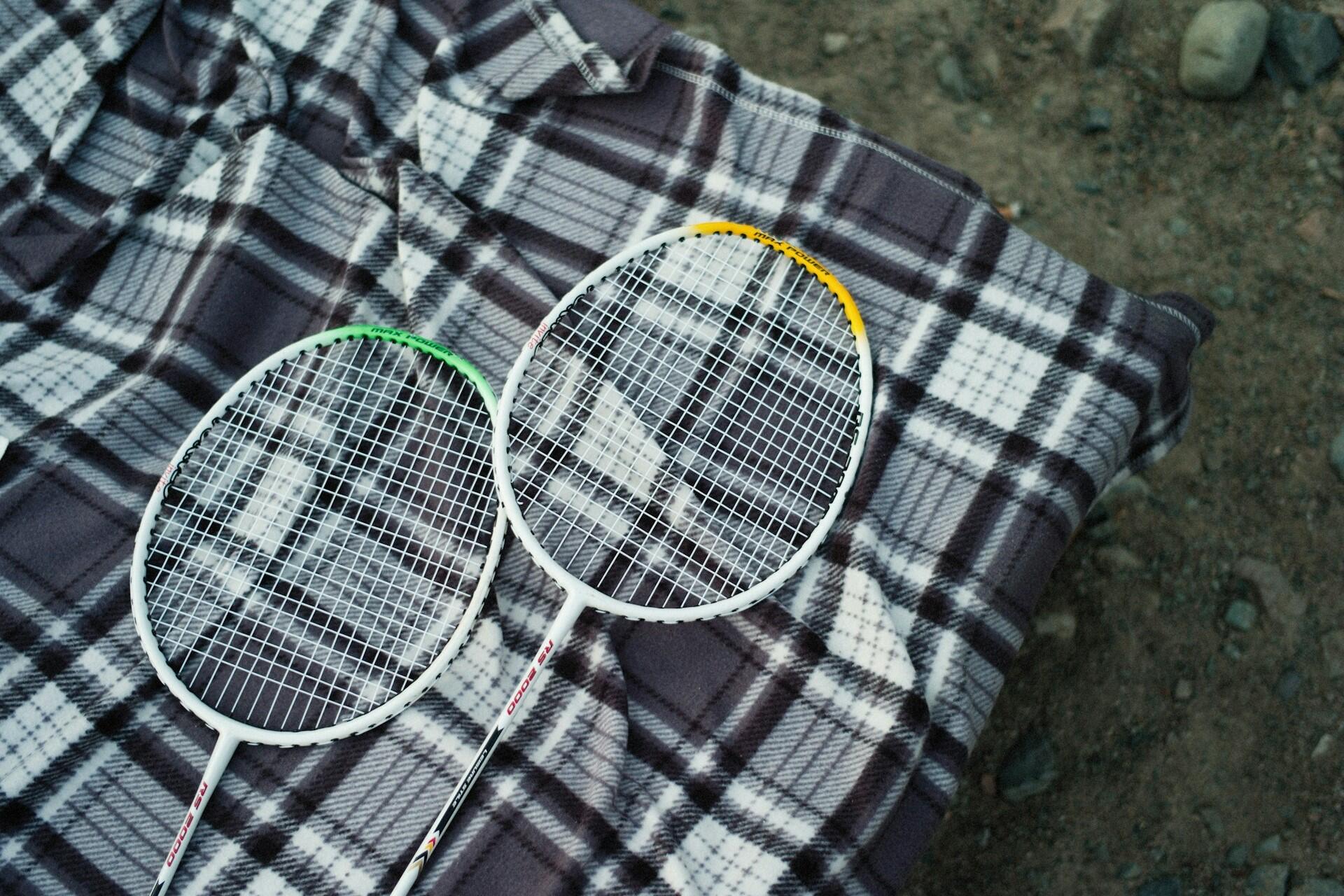 Two badminton racquets on a picnic blanket.