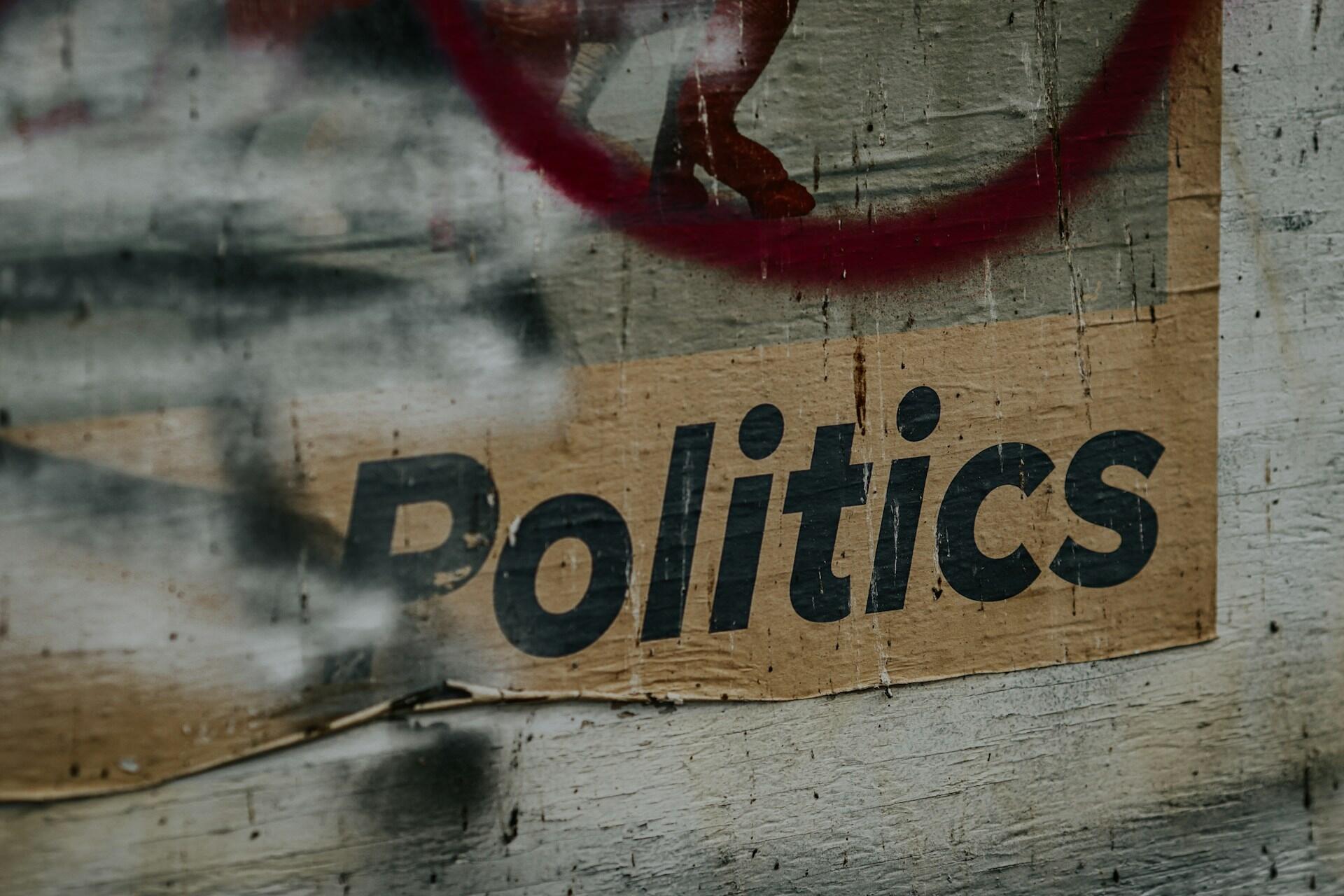A graffiti-covered poster with the word 'politics' in big black letters.
