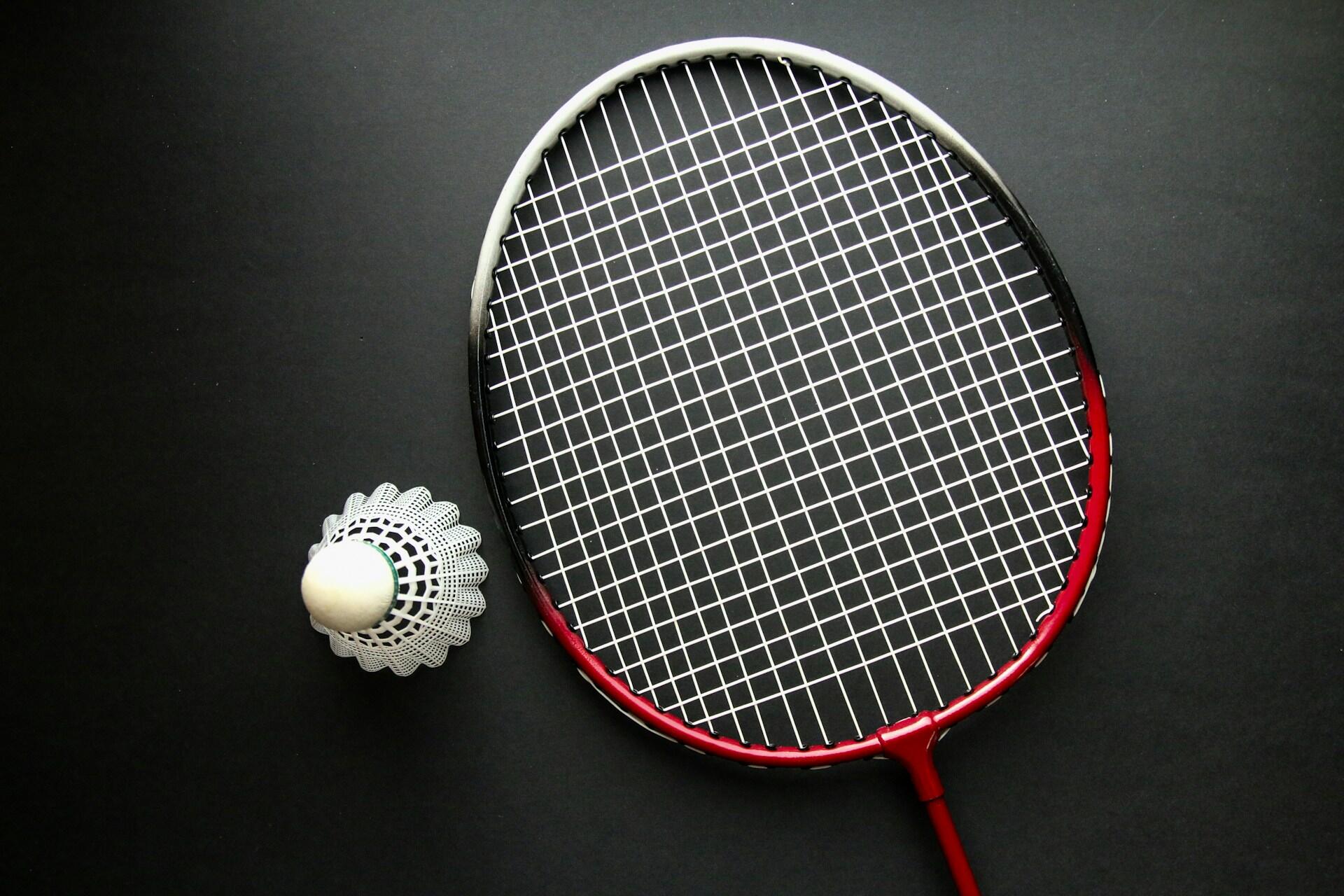A shuttlecock next to a racquet.