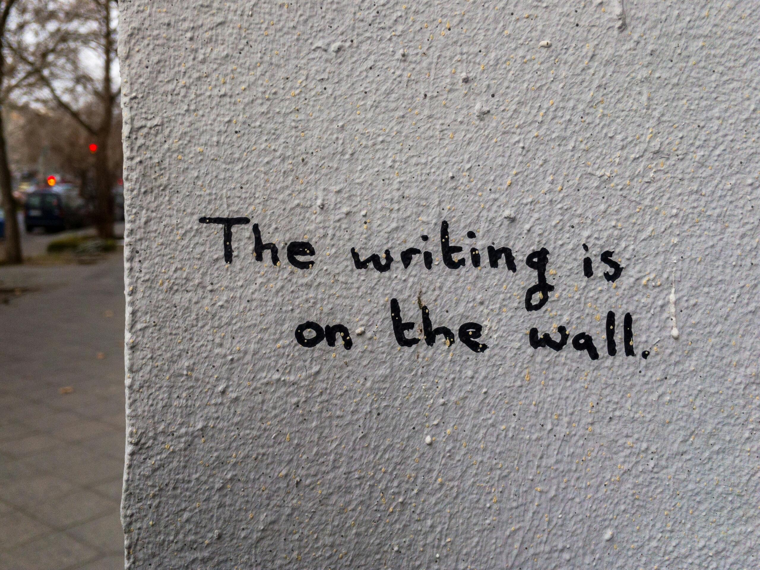 A wall with the idiom 'The writing is on the wall' written on it in grafitti