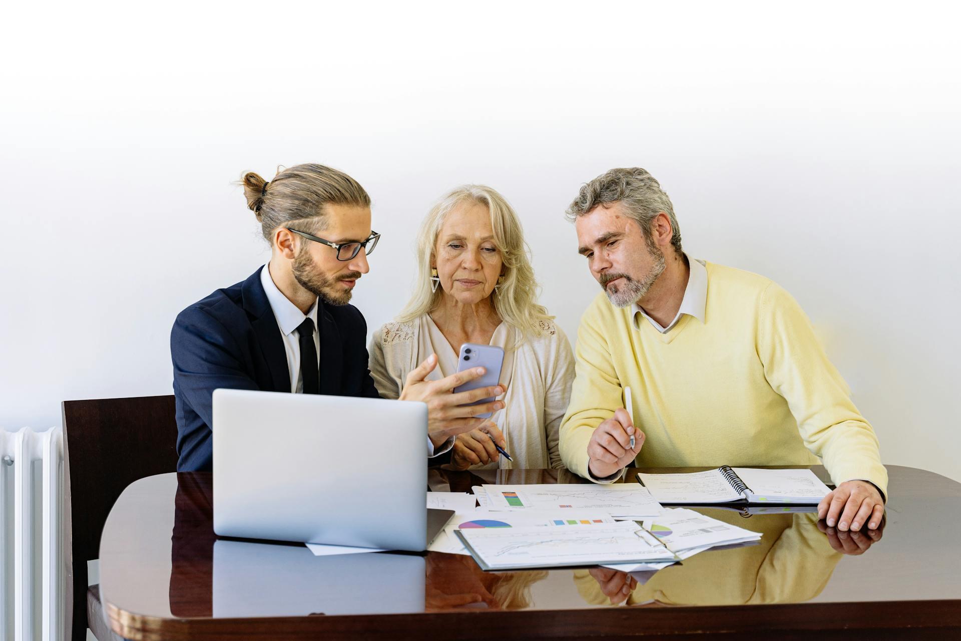 three people sitting on a desk discussing over work
