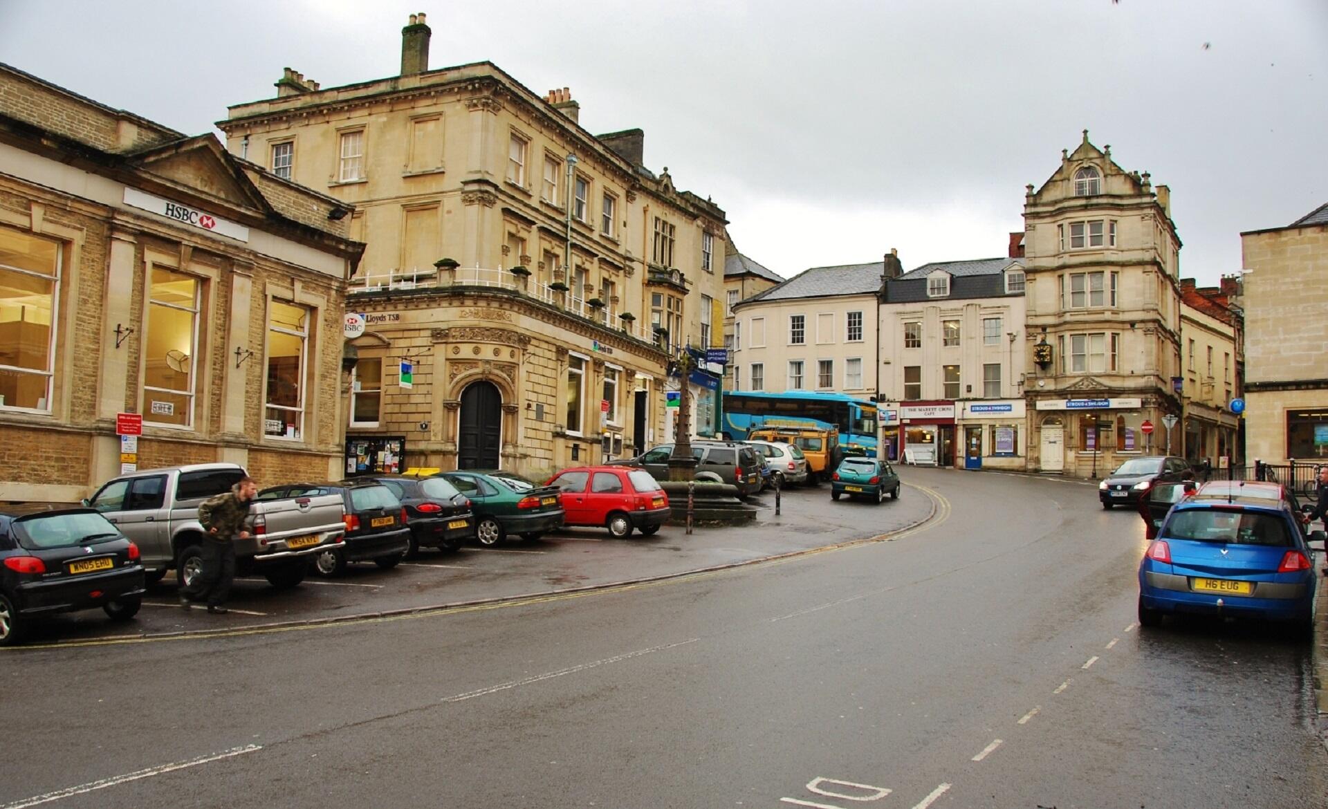 A street lined with cars and light-coloured buildings.
