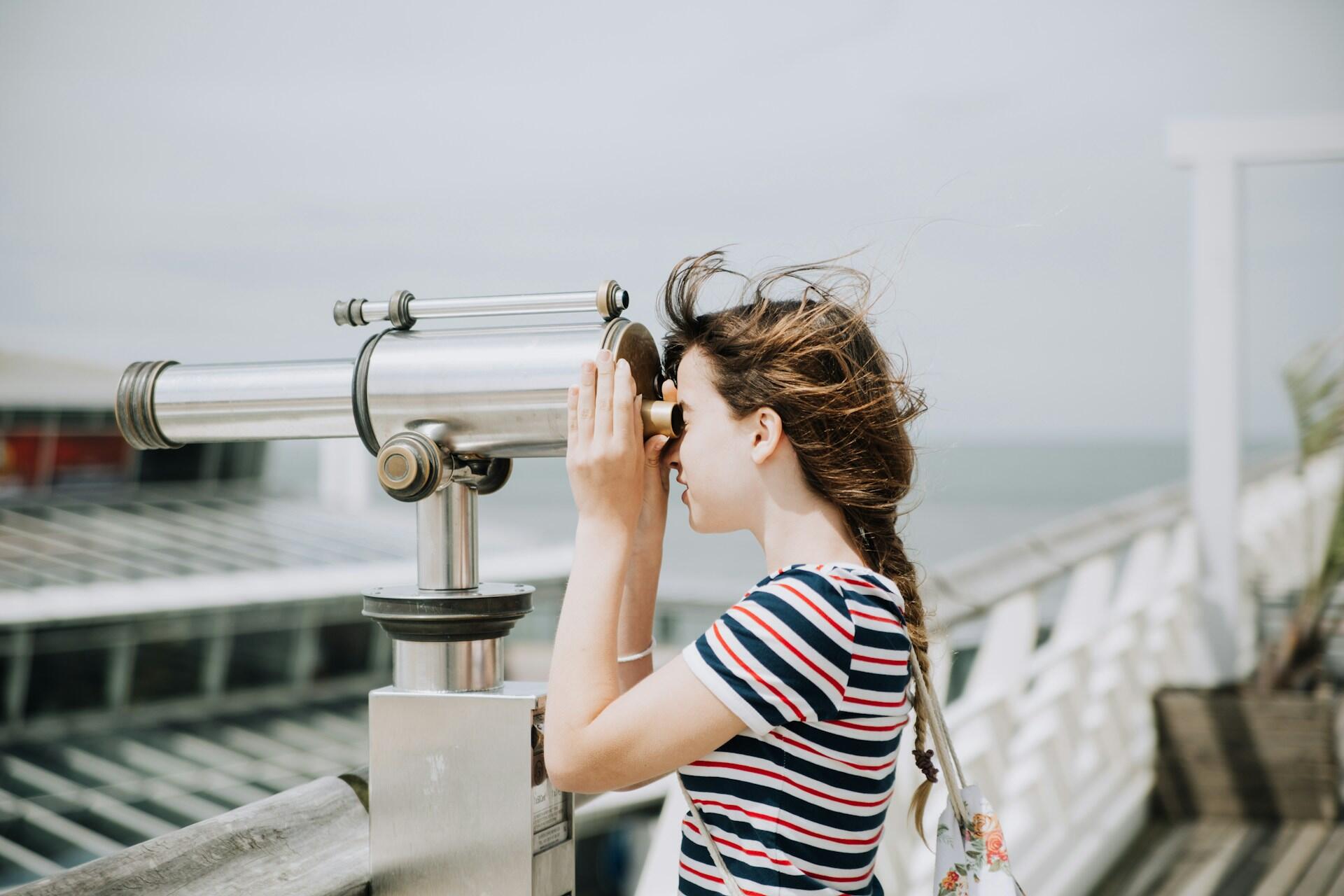 A person in a striped shirt looking through a telescope.