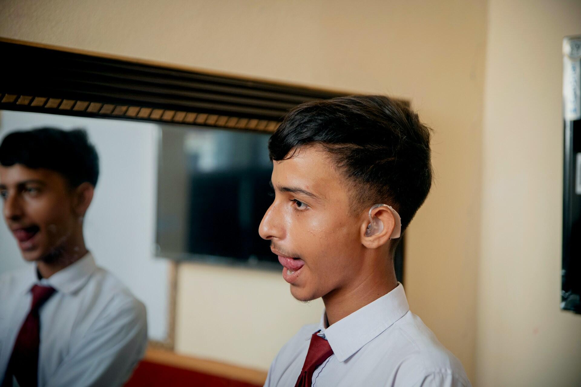 A person wearing a shirt and tie in front of a mirror.