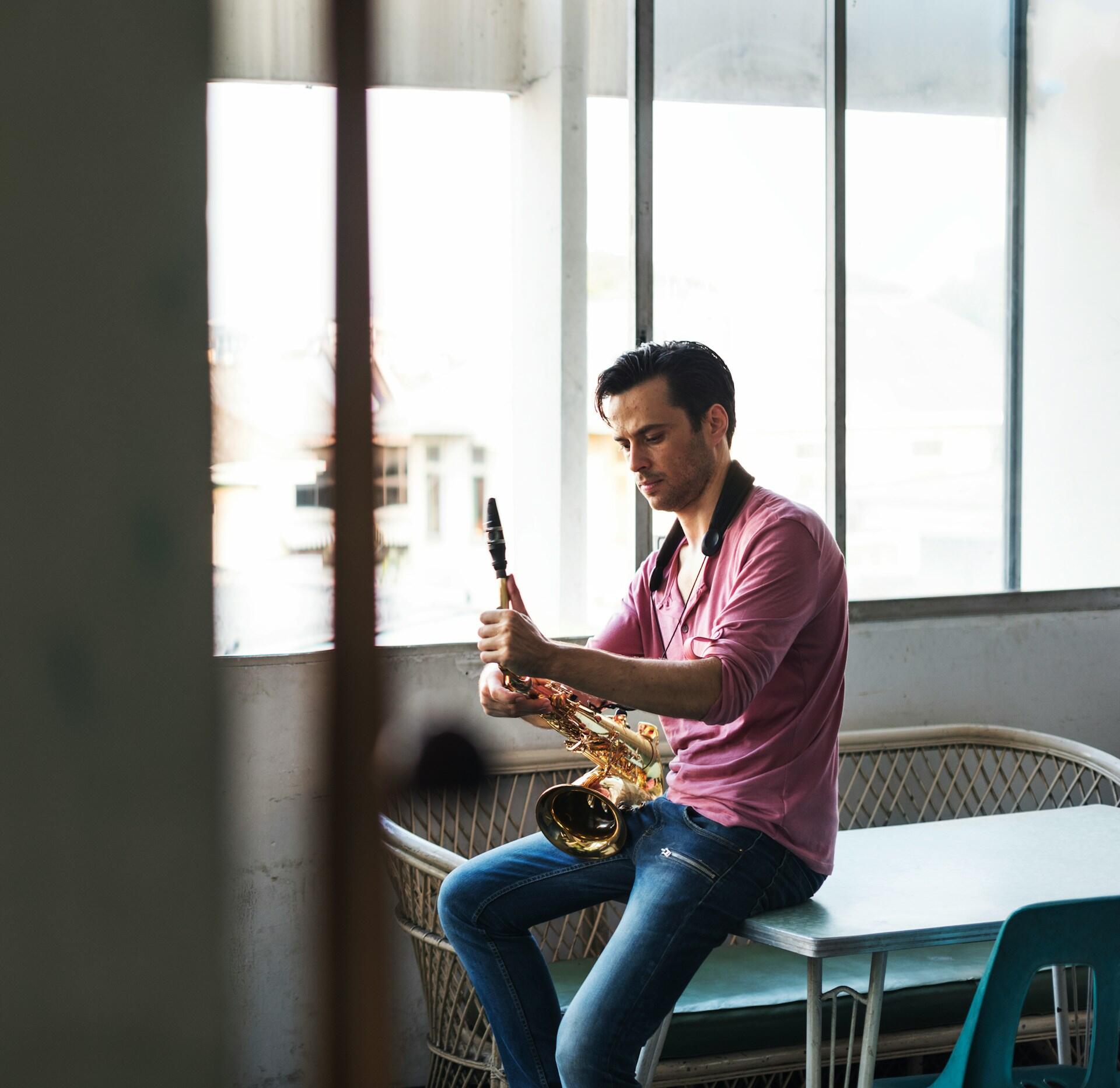 A man in a pink shirt holding a saxophone.