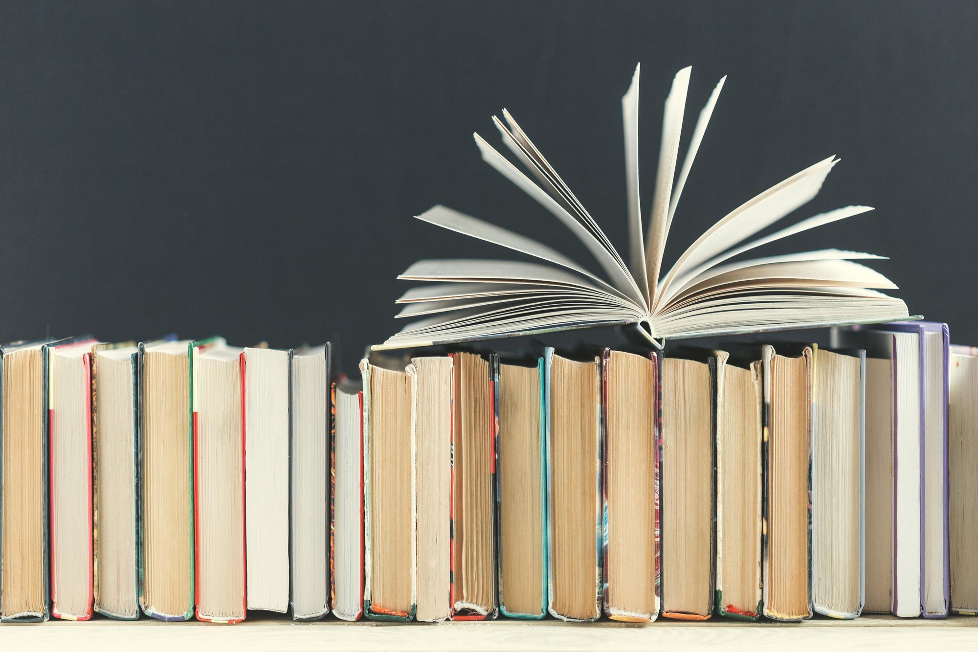 a line of books with one on top with its pages fanned open