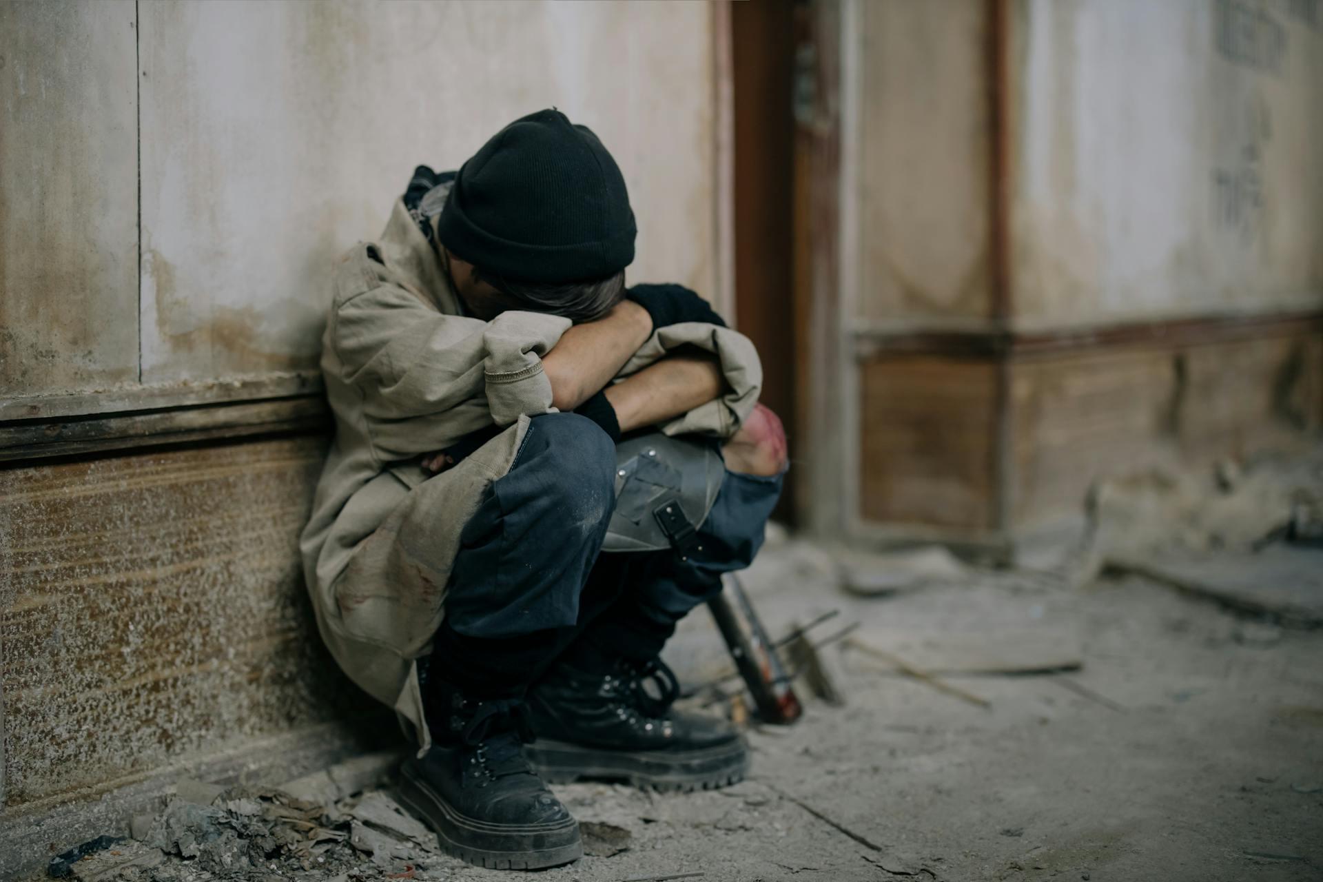 child crouched down and crying, covering their face