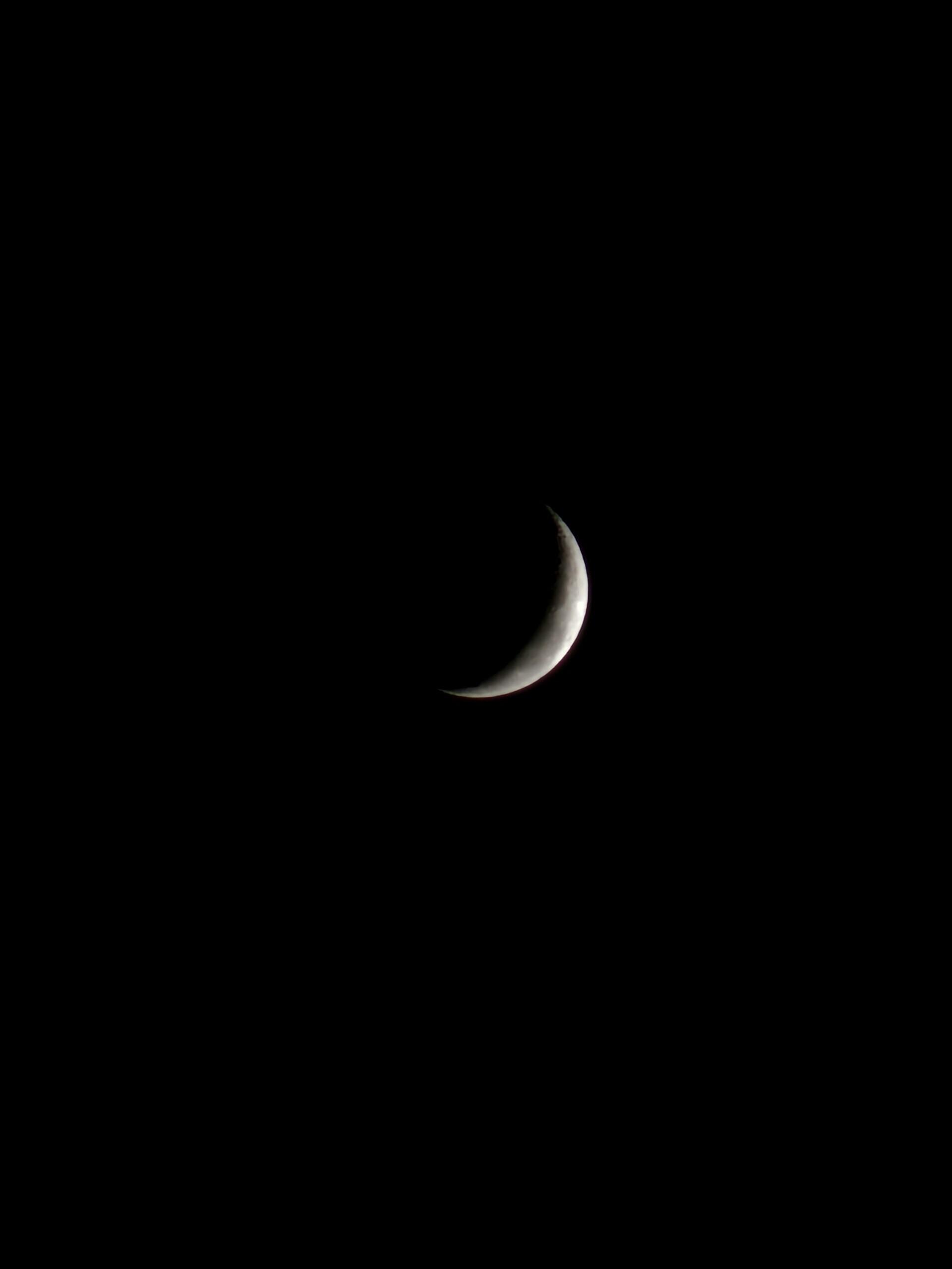 A crescent moon illuminated against a black sky, showcasing its smooth curves and subtle shading.
