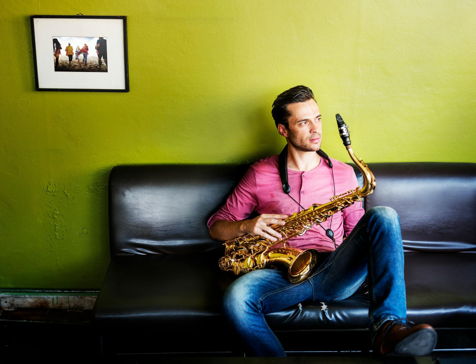 A man sitting on a couch holding a saxophone.