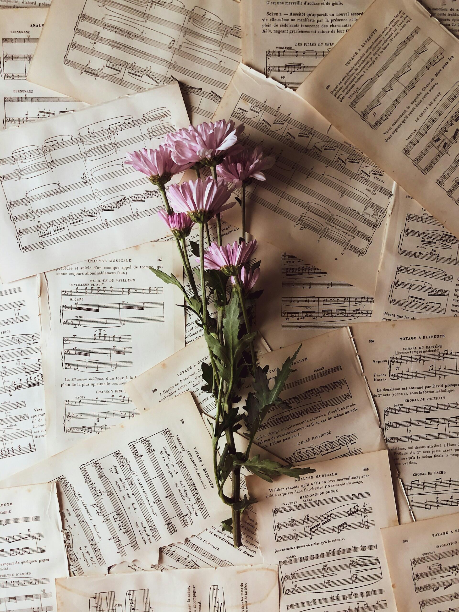 A scatter of sheet music with a bunch of flowers on it. 