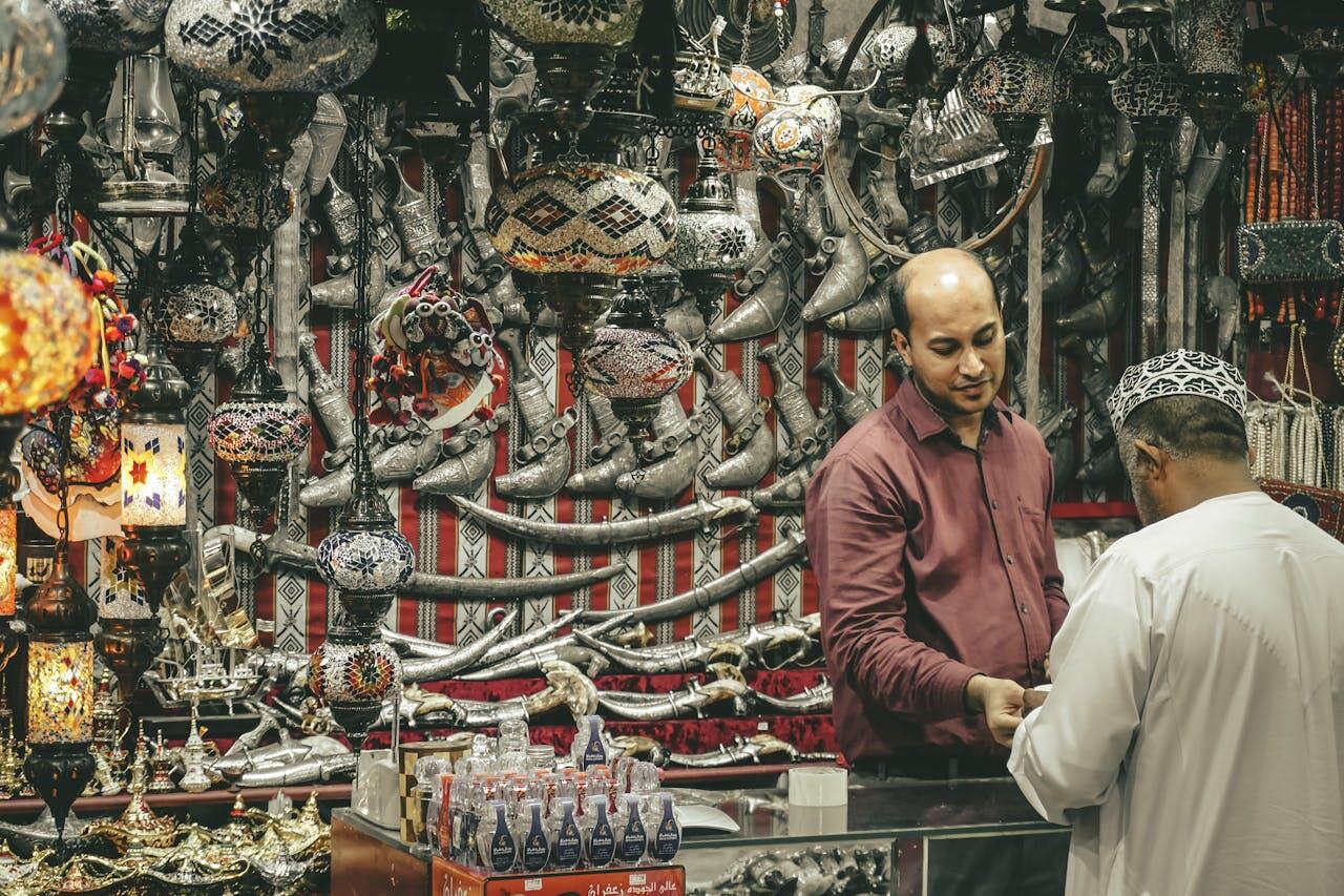 A vibrant marketplace stall showcasing intricately designed lamps, silver artifacts, and traditional ornaments against a striking tapestry backdrop.