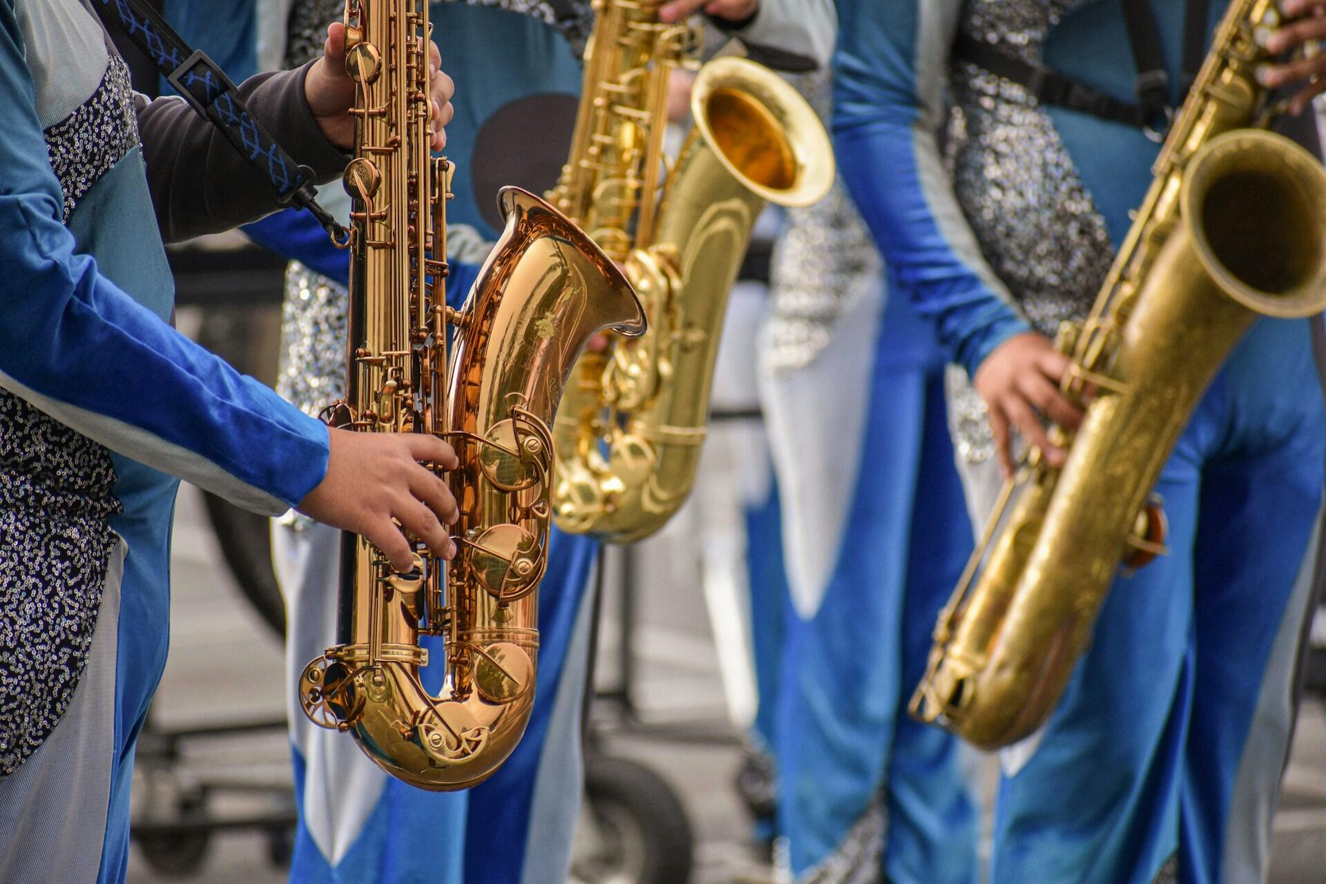 People in blue and silver uniforms holding saxophones.