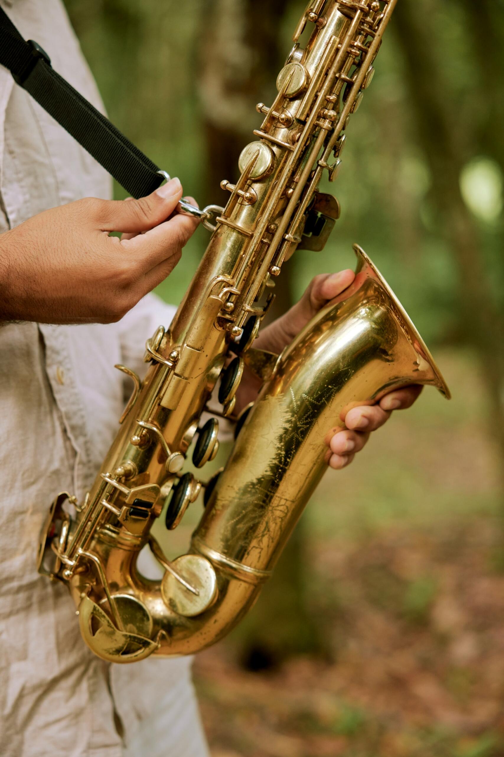 A person attaches a neck strap to their saxophone.