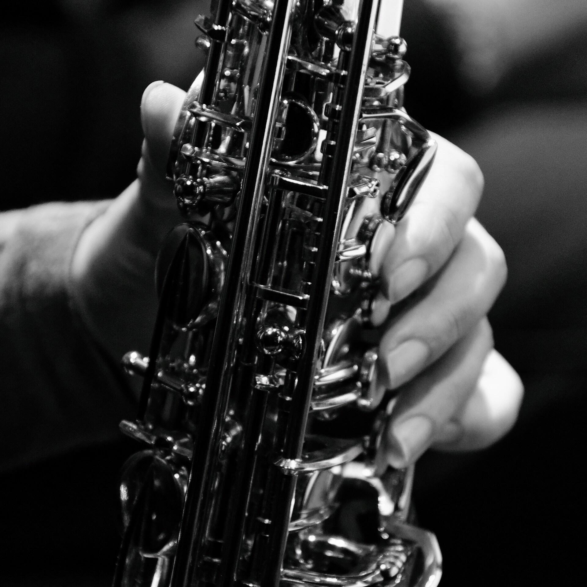 A closeup of a saxophone body with a hand near the keys. 