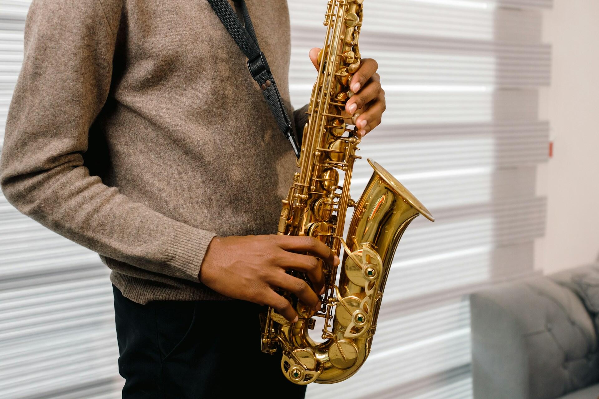 A person in a brown jumper holding a sax.