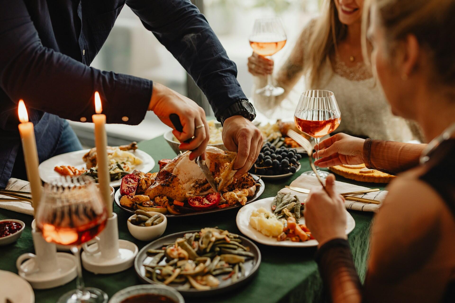 people seated around a thanksgiving table with turkey and various foods