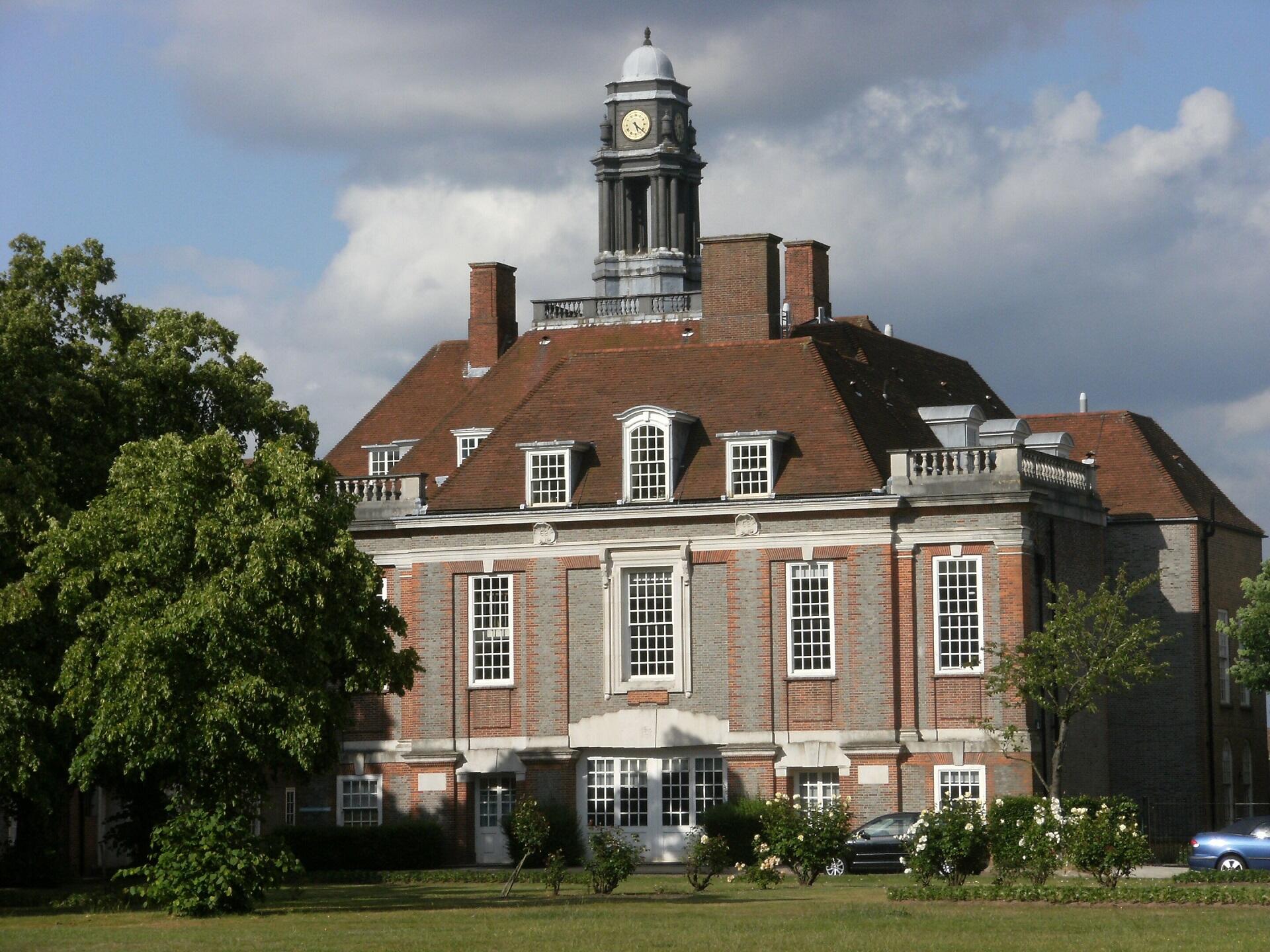 A large building with an ornate roof and a green lawn in front of it.