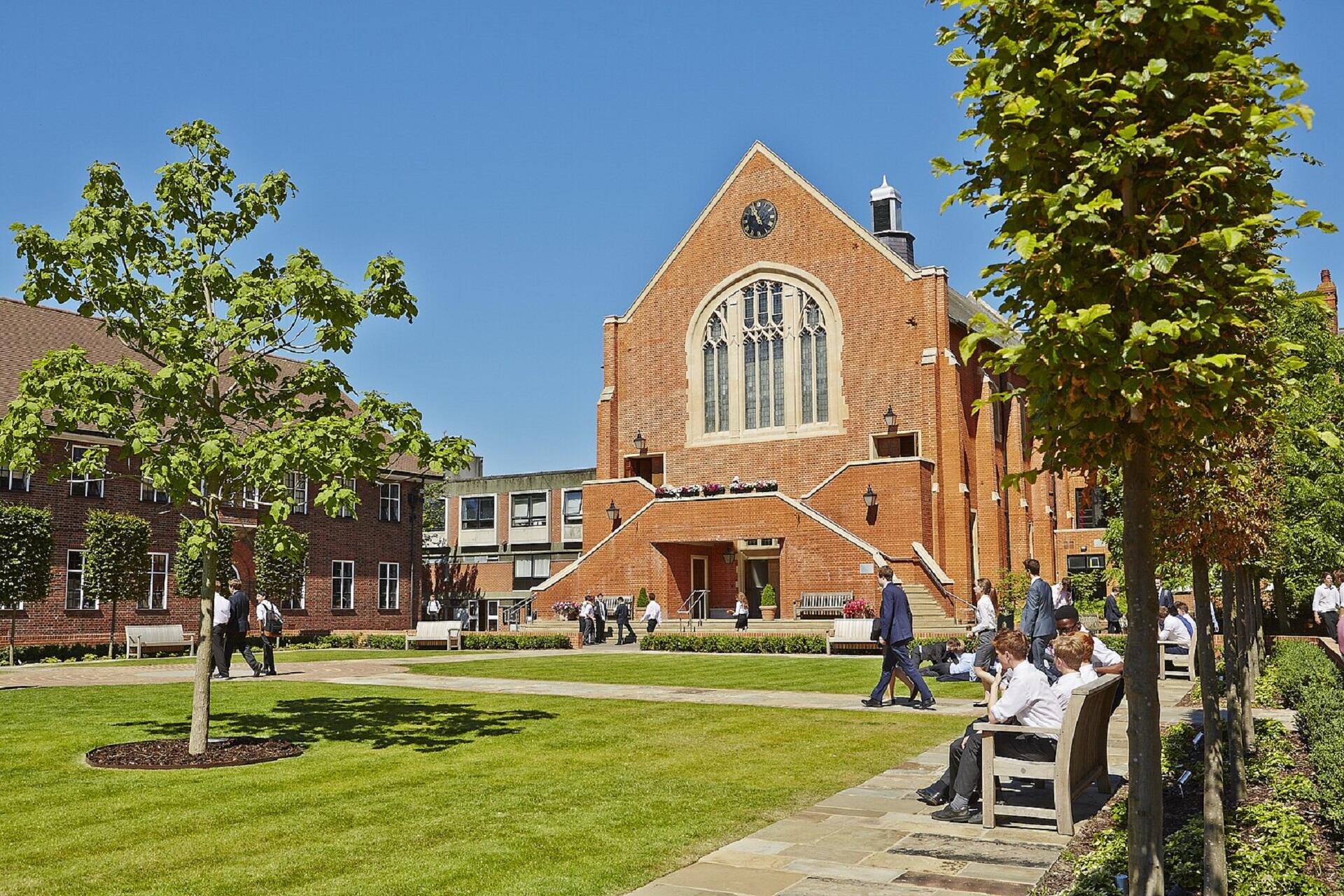 A large brick building with a green space in front of it on a sunny day.