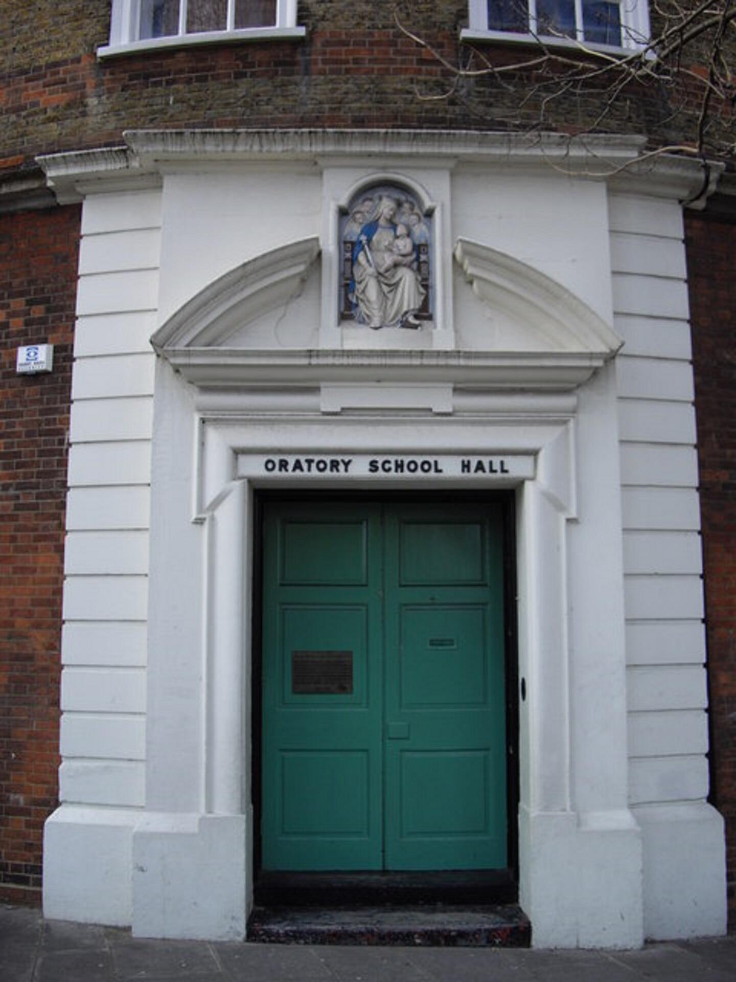 A green door surrounded by a wide white frame with an adornment above it.