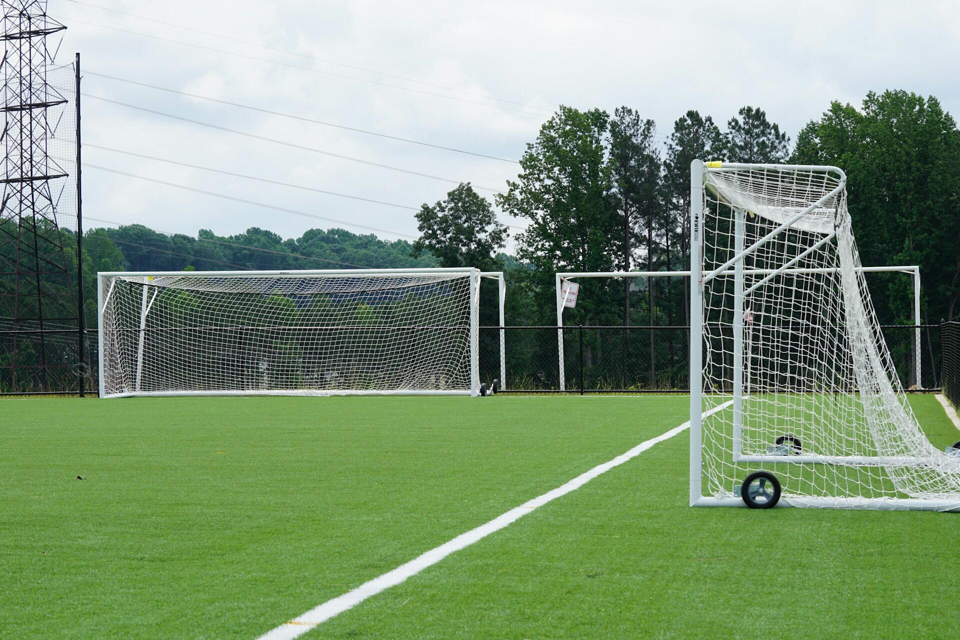 A football pitch with three practice nets aligned around it.
