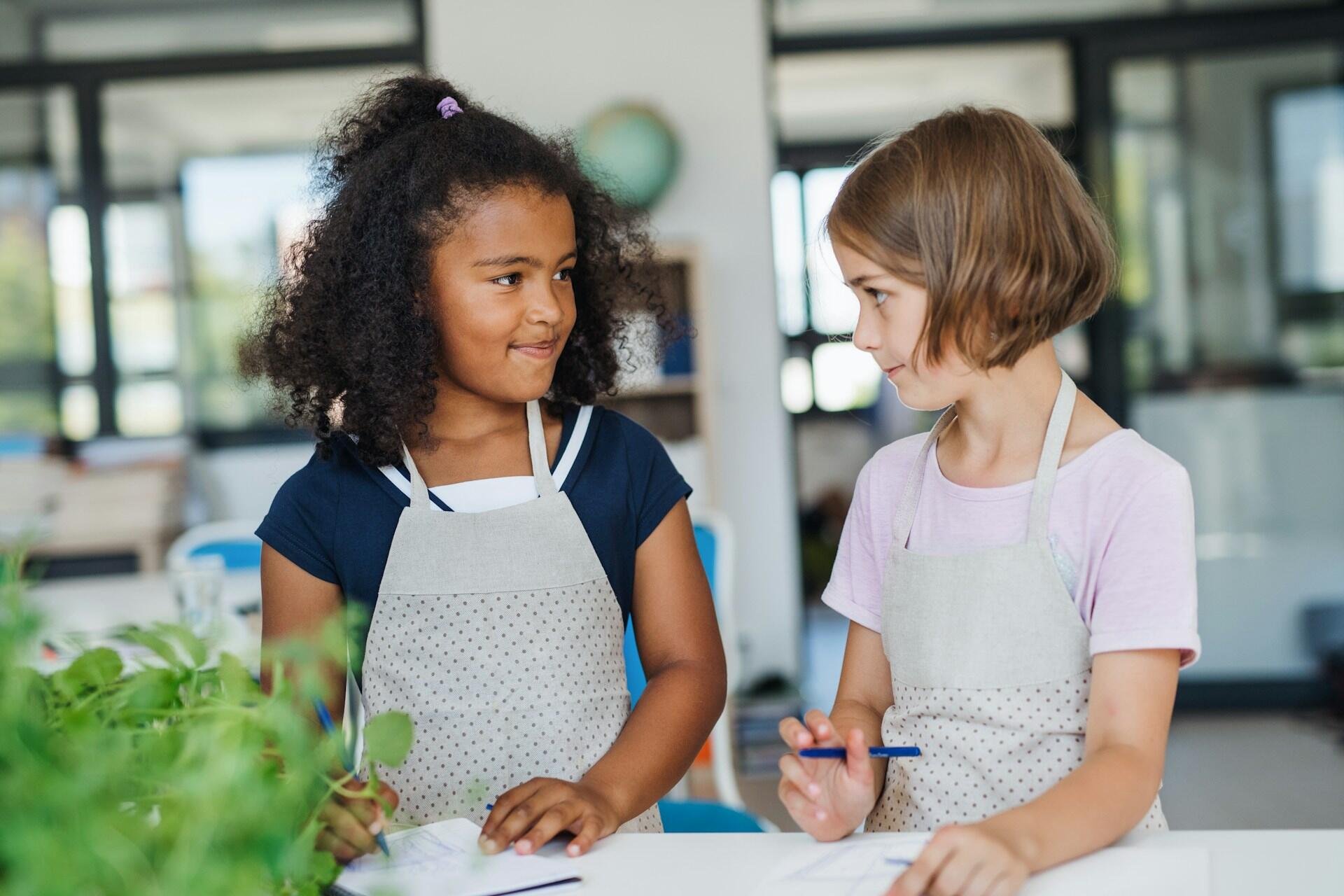 Two girls in a laboratory next to a green plant.