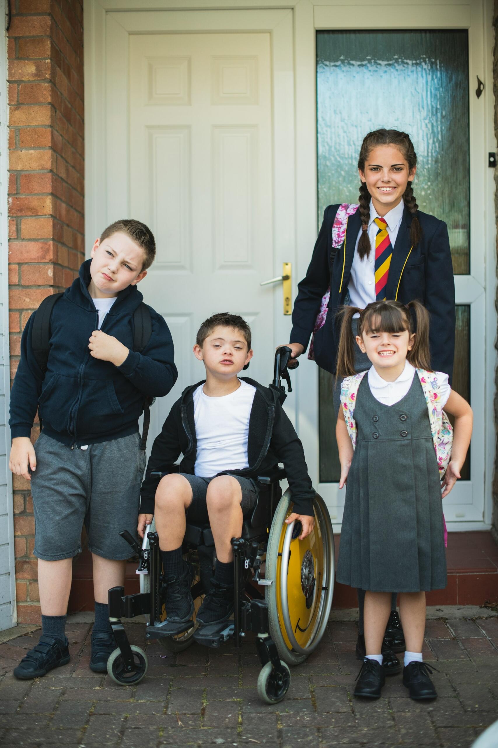 Four students in school uniforms in front of a brick building.