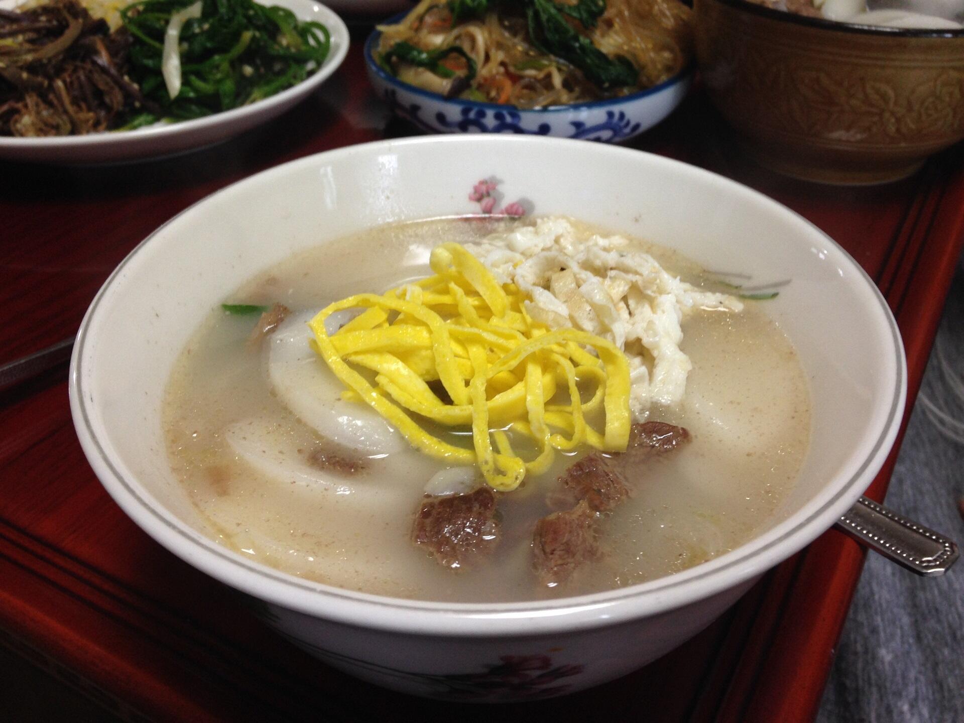 A bowl of soup with yellow and white garnish. 