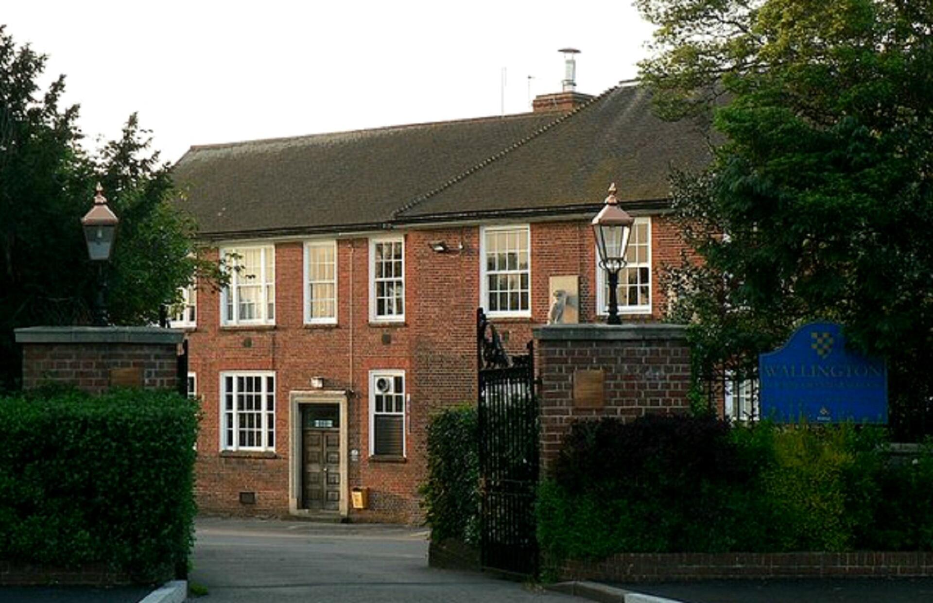 A red brick building behind hedges.