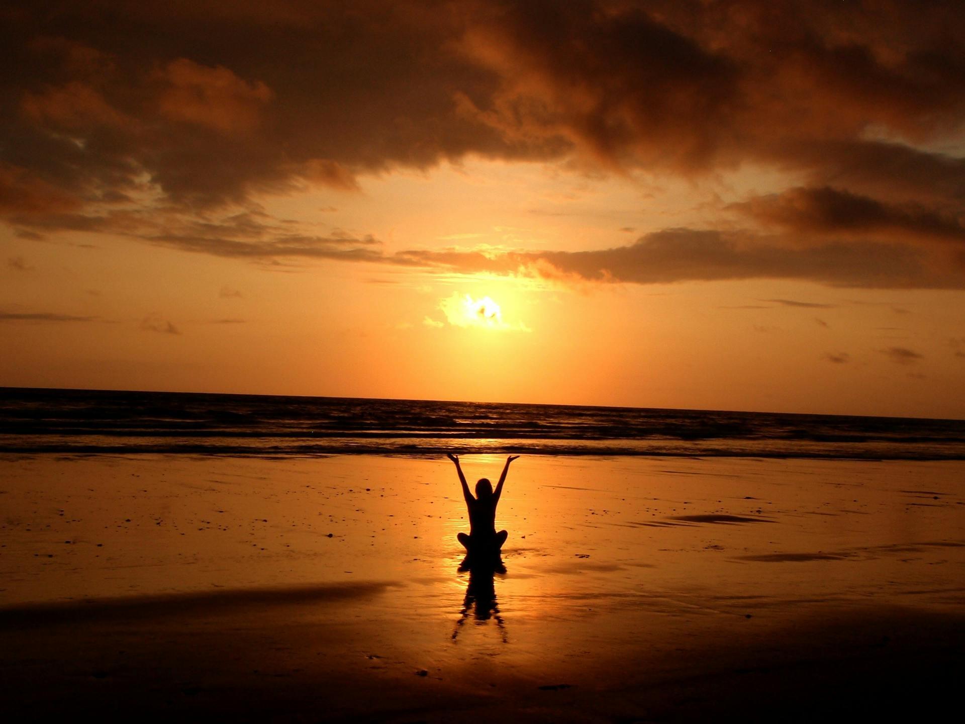 Woman doing yoga on a beach during sunrise