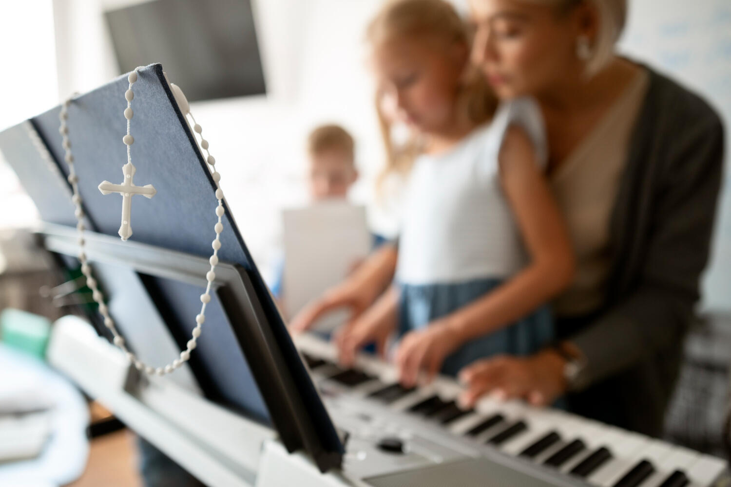 music teacher for children's church choir showing a child how to pay piano