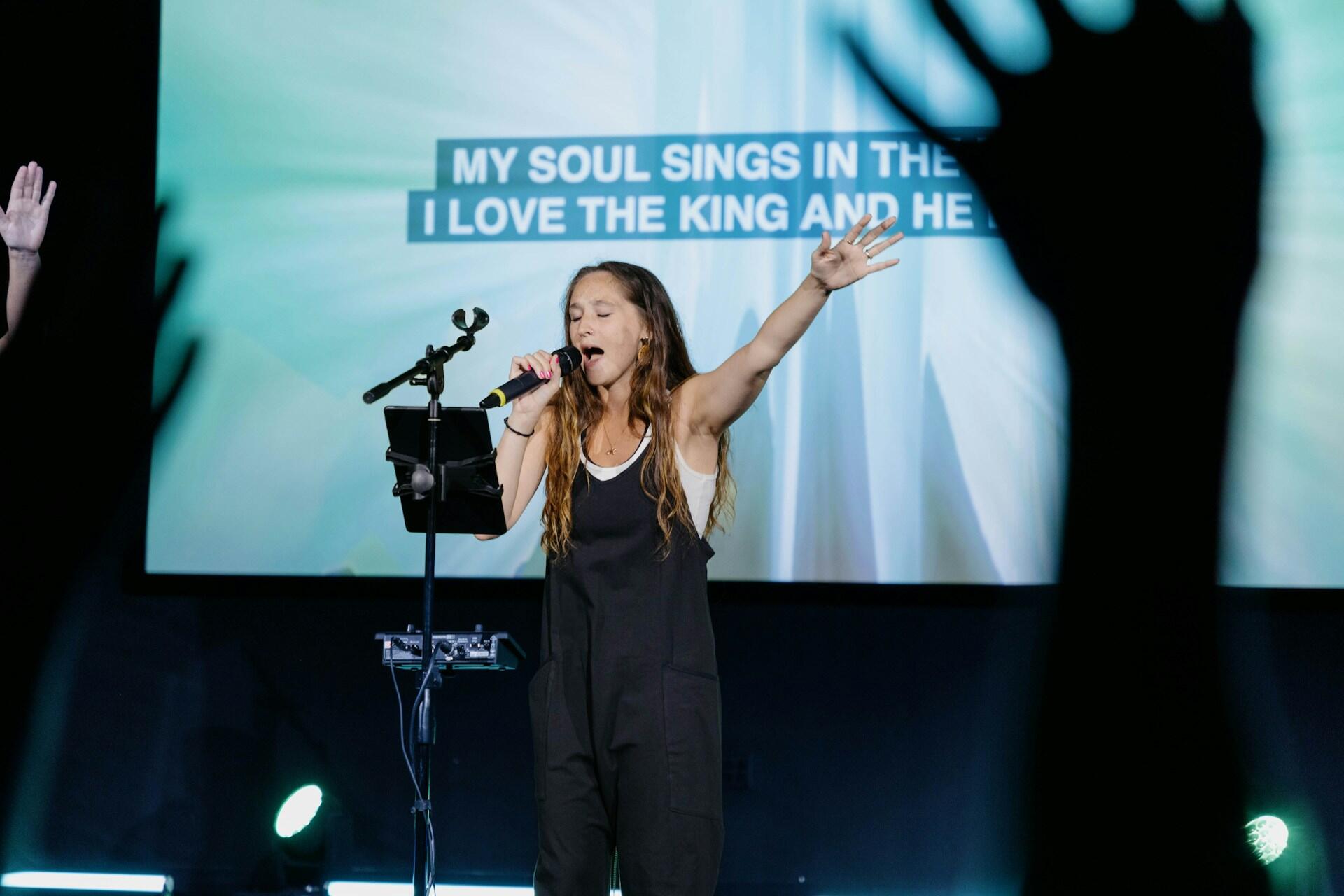 church singer on stage with projection display on the back wall
