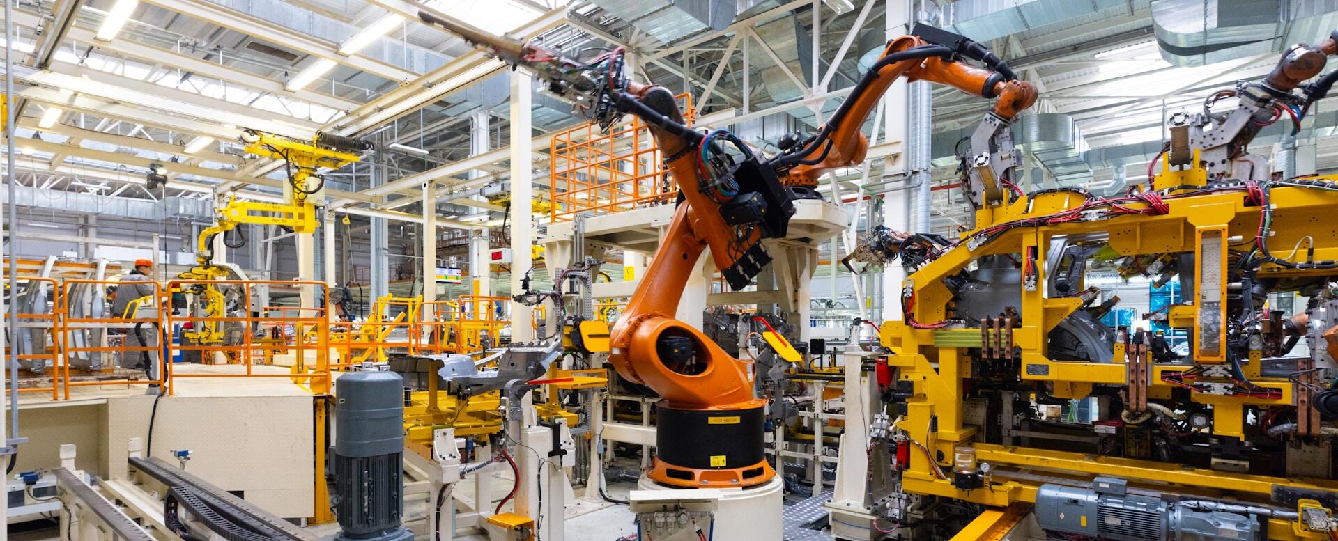 A factory floor with large, orange robotic arms.