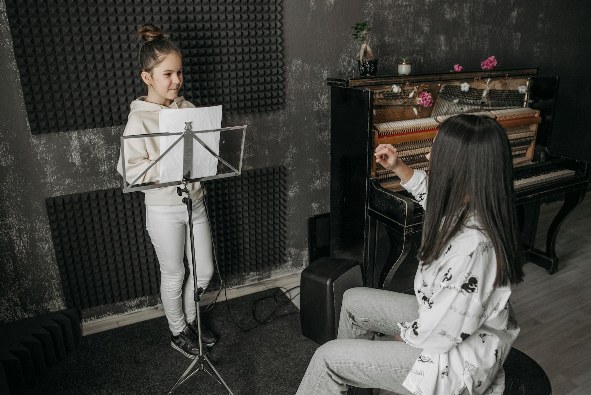 Photo of girl practicing singing with teacher gesturing 