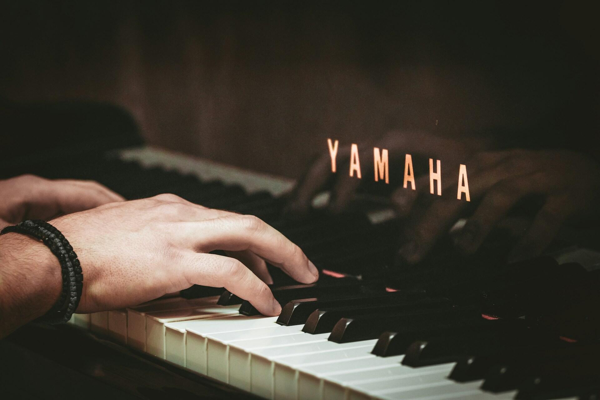 Hands playing a Yamaha piano keyboard