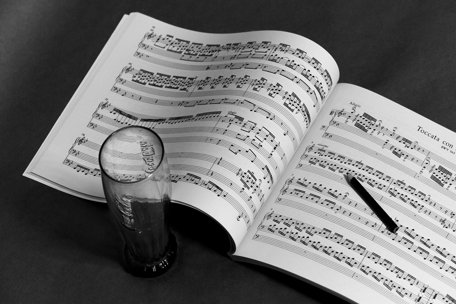 Open sheet music book with a glass resting on the page