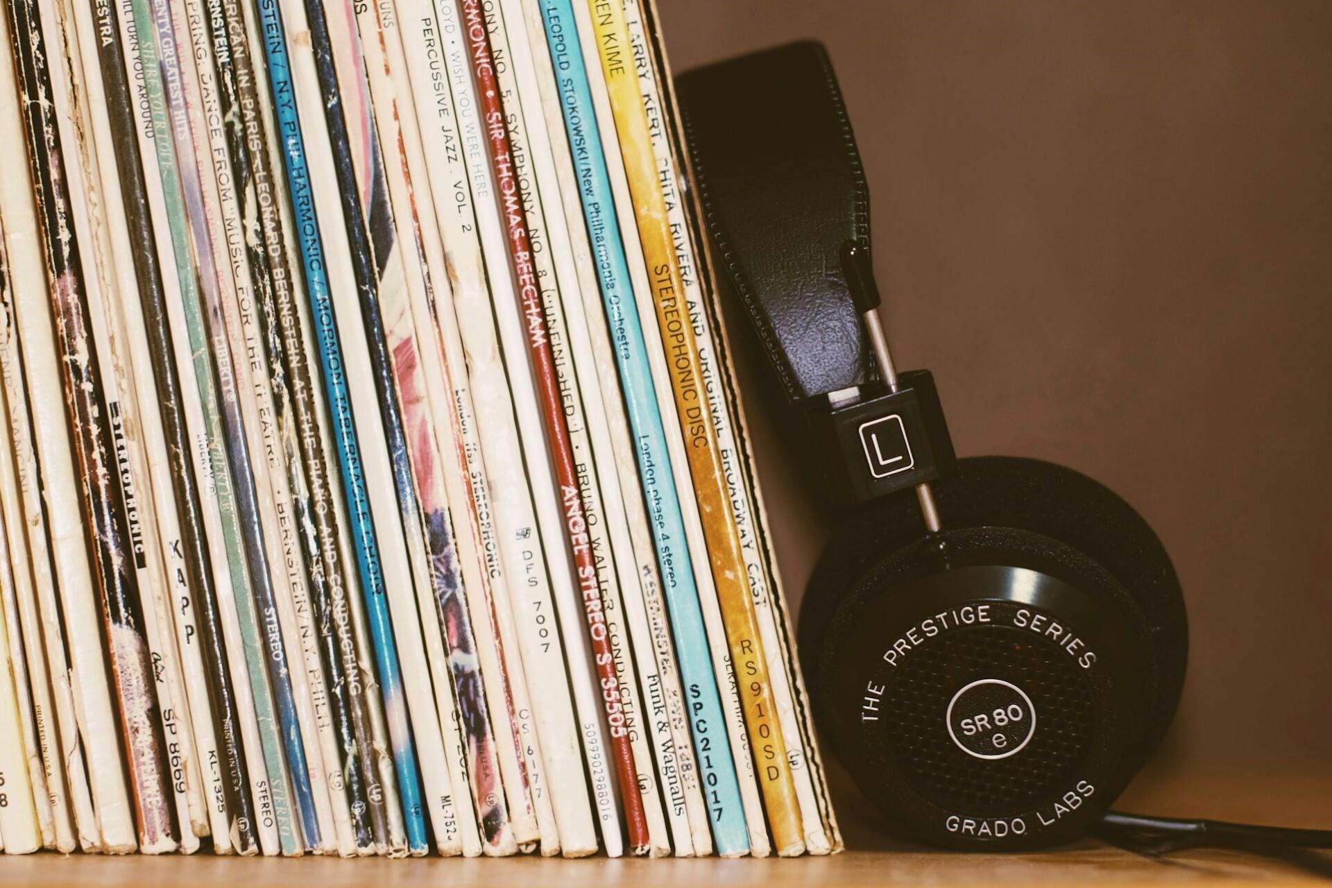 Row of vinyl record sleeves with a pair of headphones leaning against them.