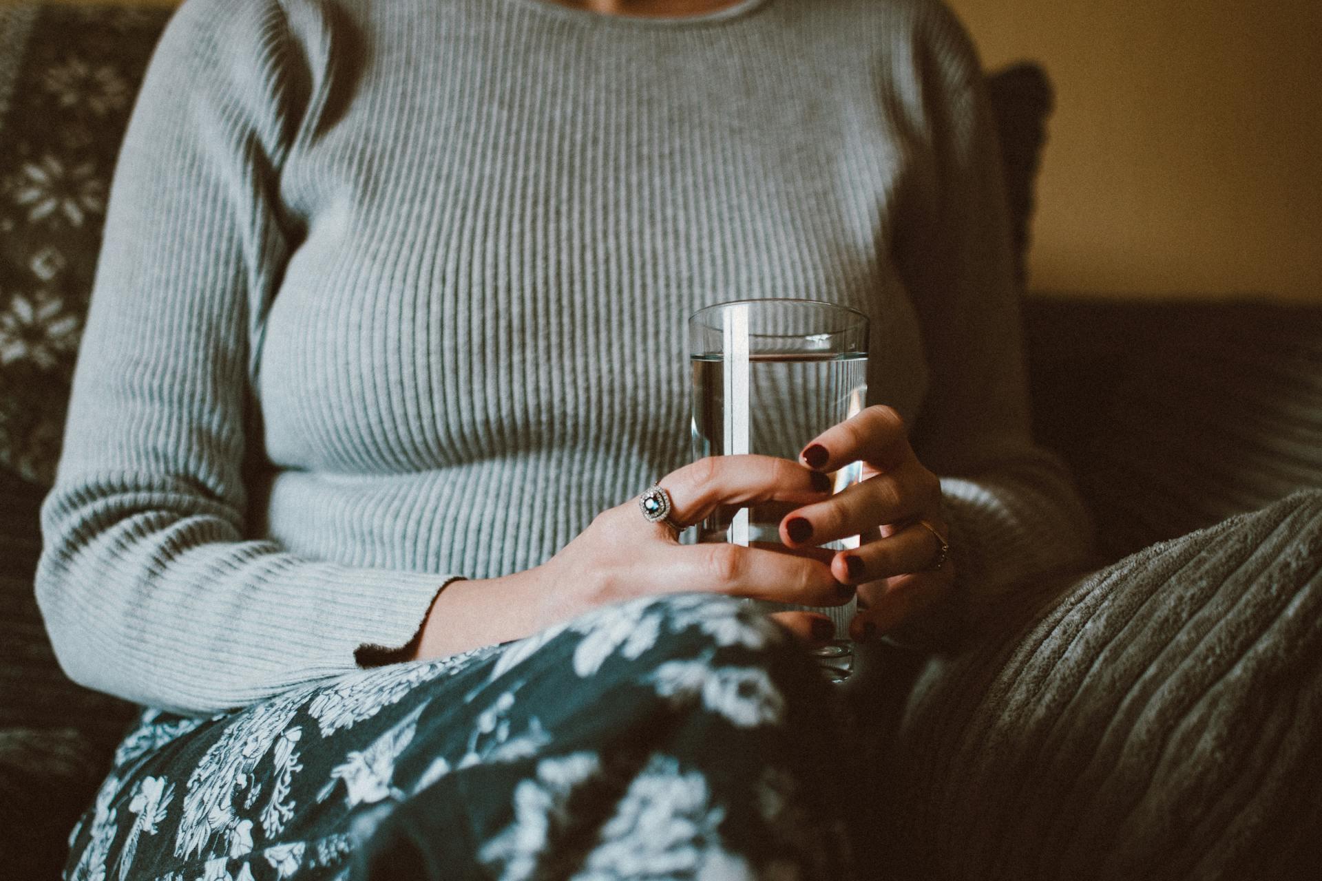 Woman sat on sofa with a glass of water in her hands 