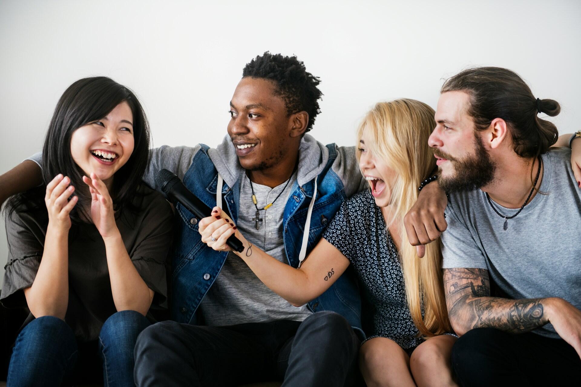 Four young adults seated close together, laughing and smiling.