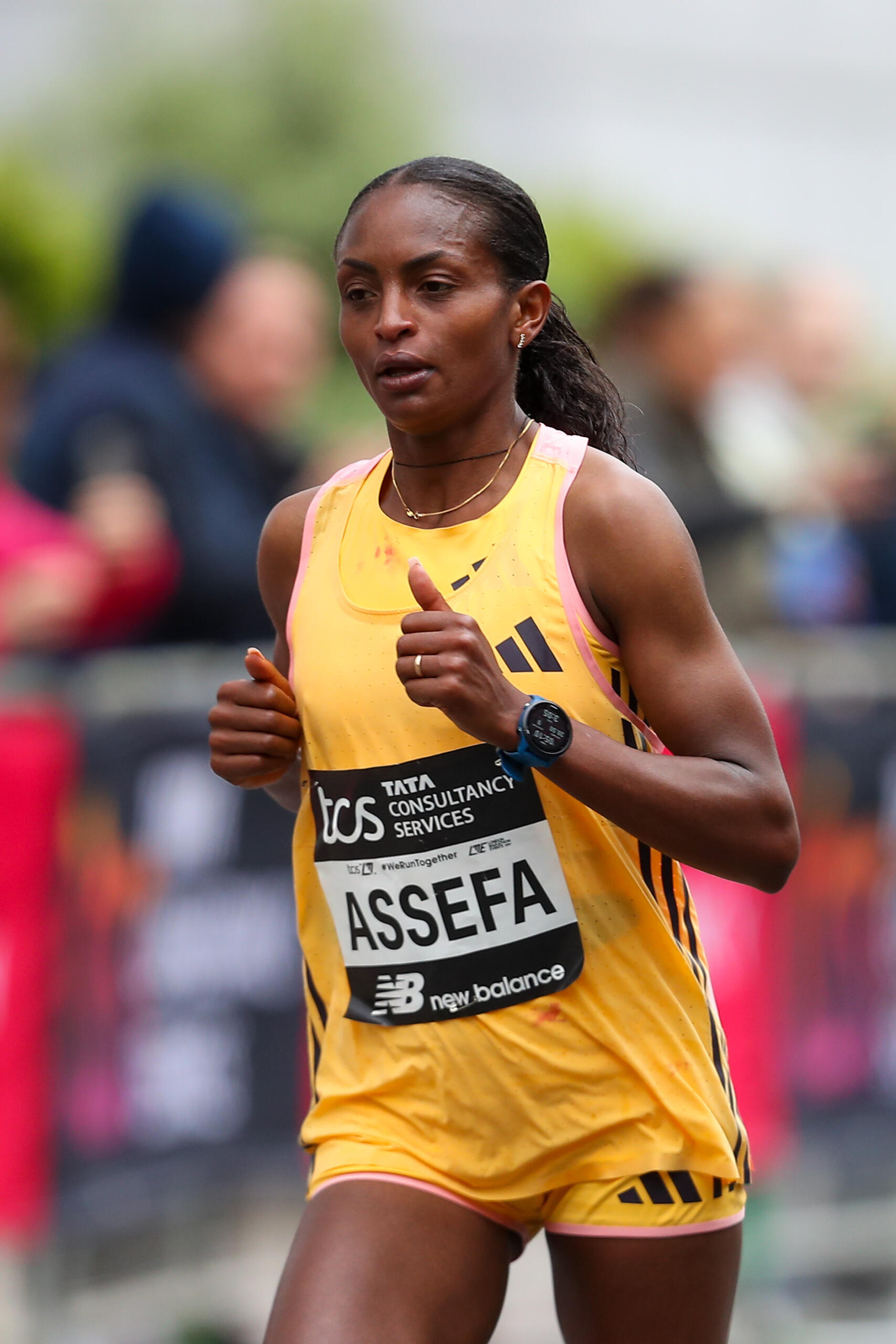 Runner Tigst Assefa wearing a yellow shirt and running in the London Marathon 2024