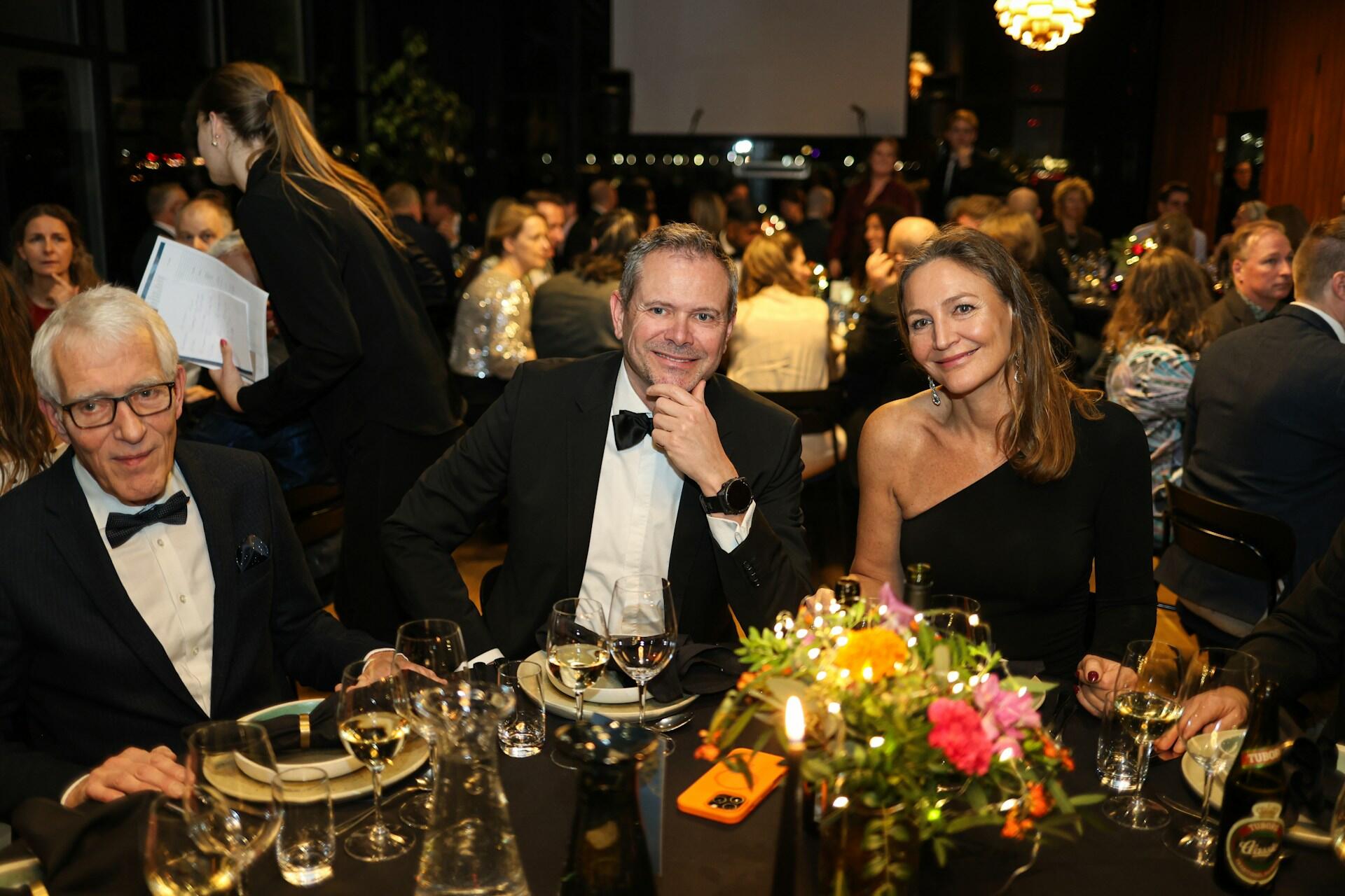 A group of people in fine clothing seated at a festive table.