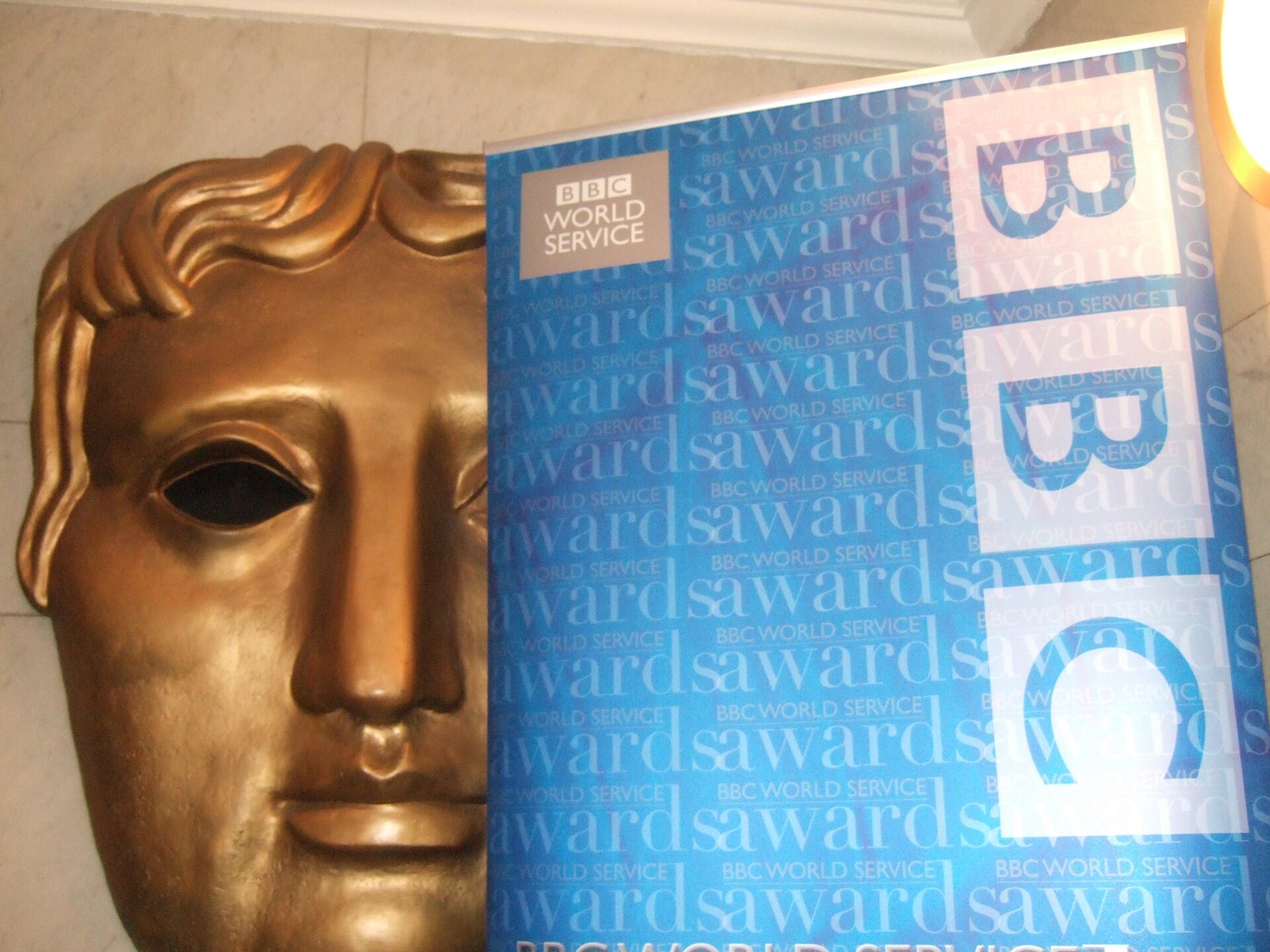A golden mask next to a blue notebook with the letters BBC on it.